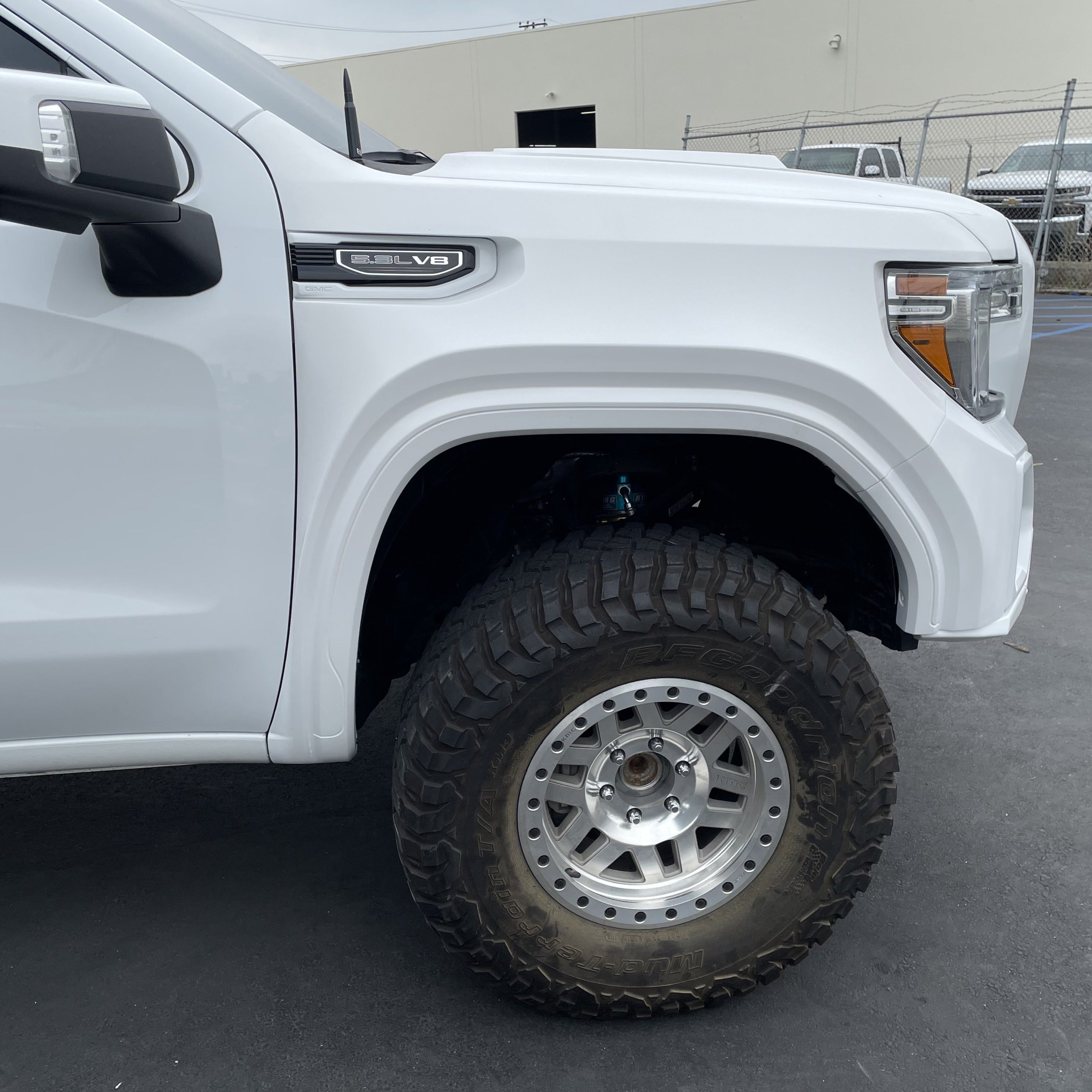 2019-2025 GMC Sierra fenders showcasing a white truck with oversized tires, emphasizing durability and style.