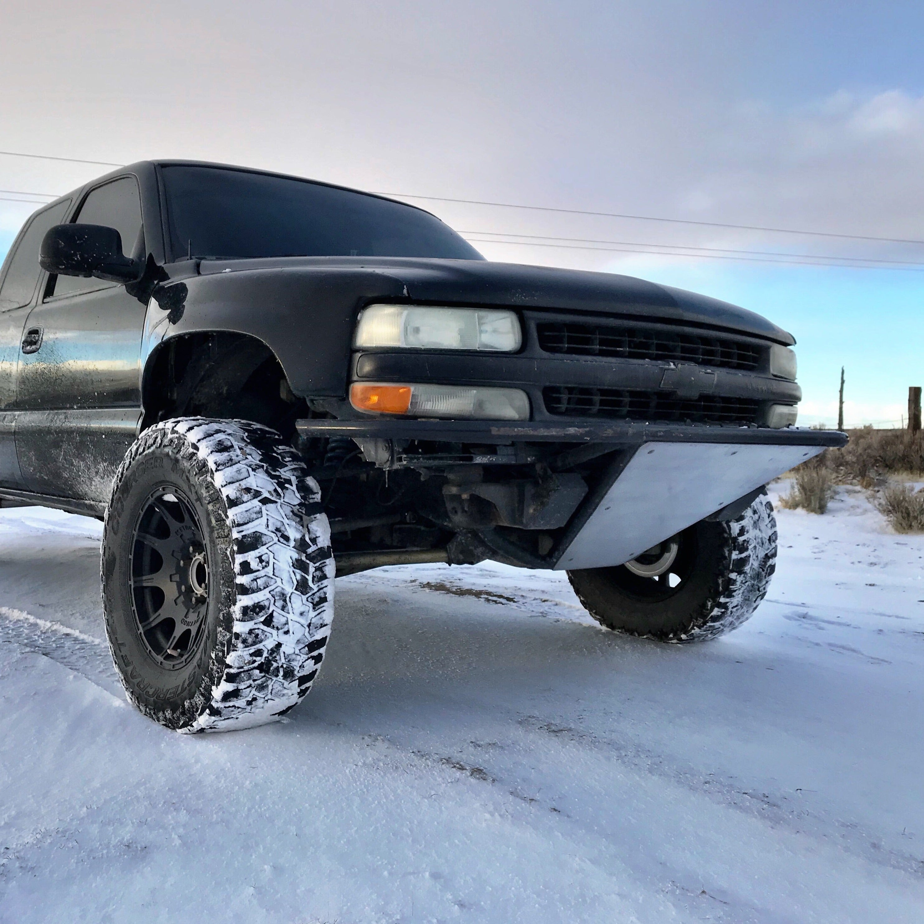 1999-2002 Chevrolet Silverado fenders installed on a lifted black truck with offroad tires in a snowy landscape.