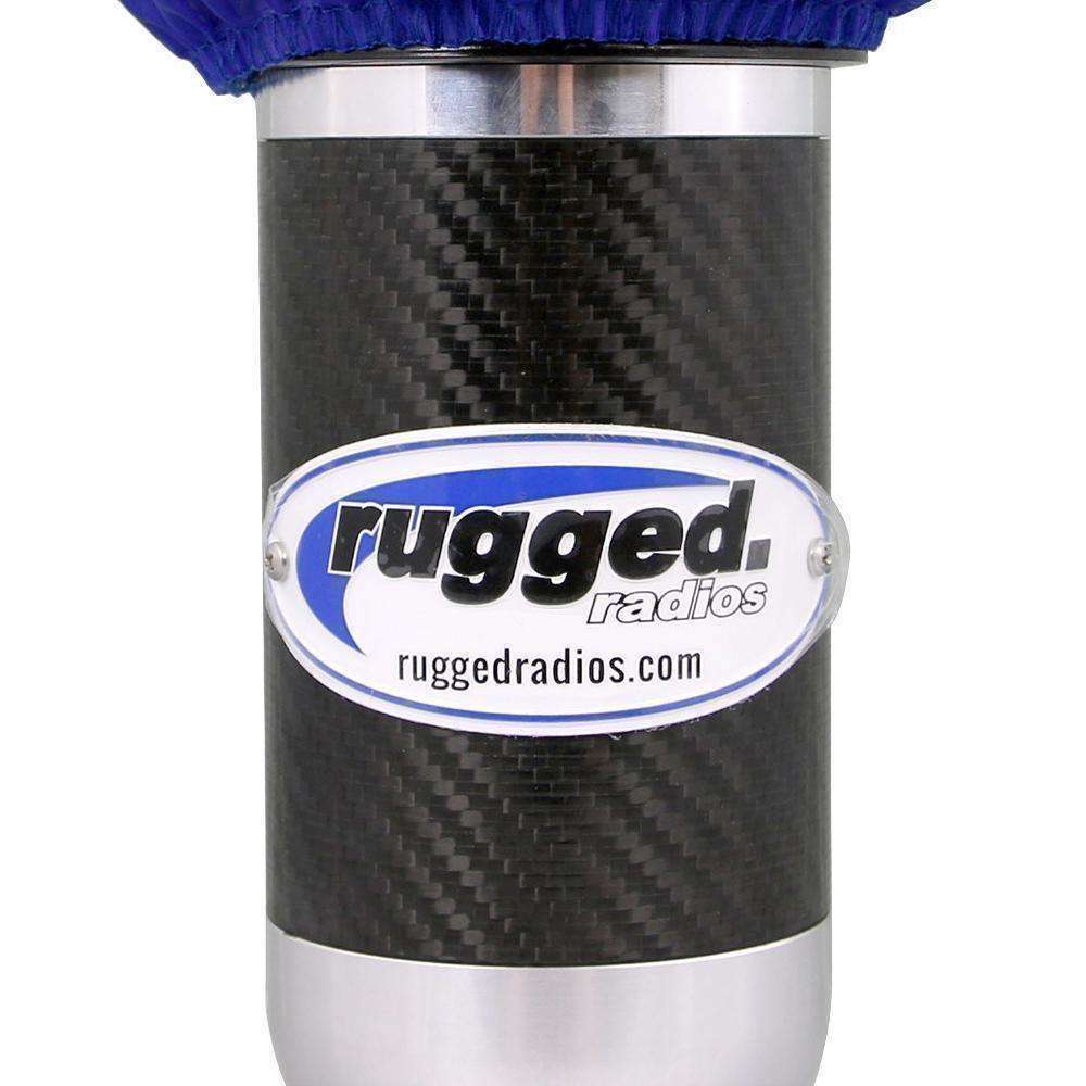 Metal embossed badge for Rugged Radios, featuring a sleek design on a carbon fiber background, ideal for offroad enthusiasts.