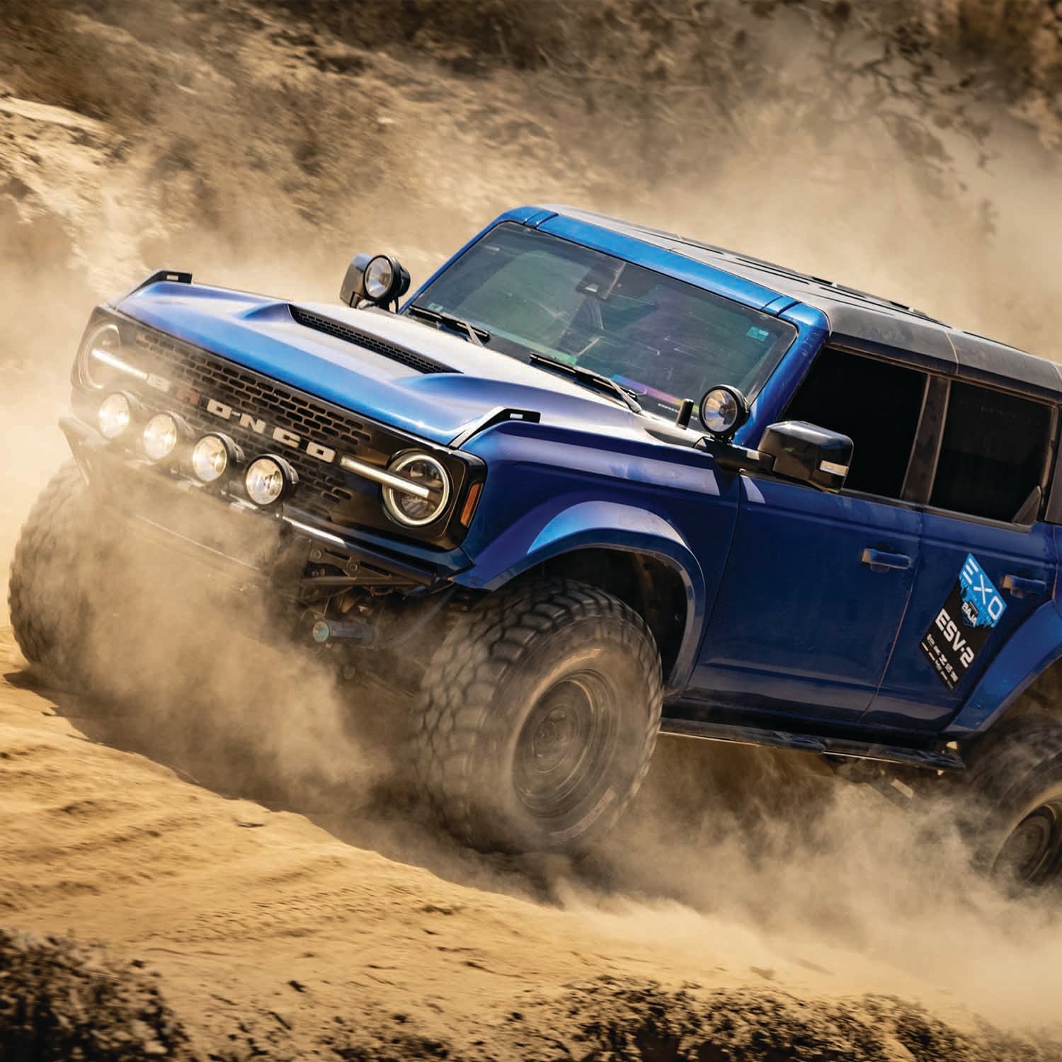 2021 Ford Bronco with Baja bumper driving through sandy terrain, showcasing offroad capabilities and rugged design.