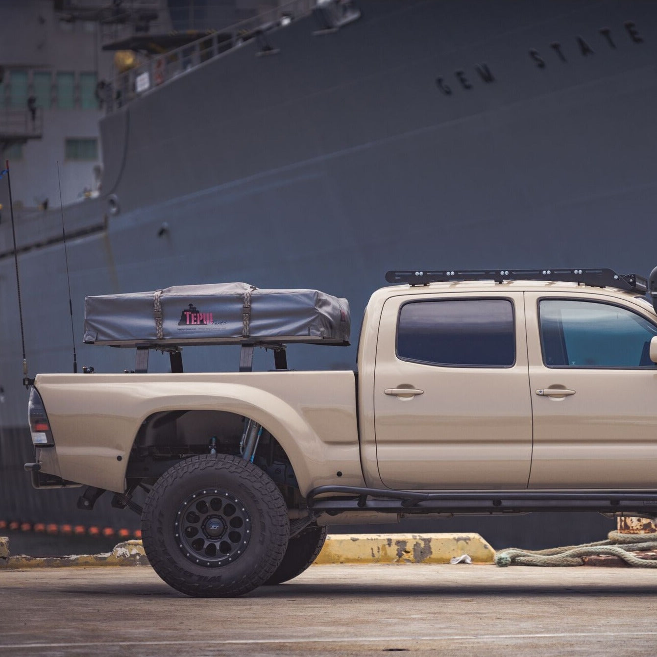 2005-2015 Toyota Tacoma bedsides installed on a modified truck with offroad accessories, parked near a large ship.