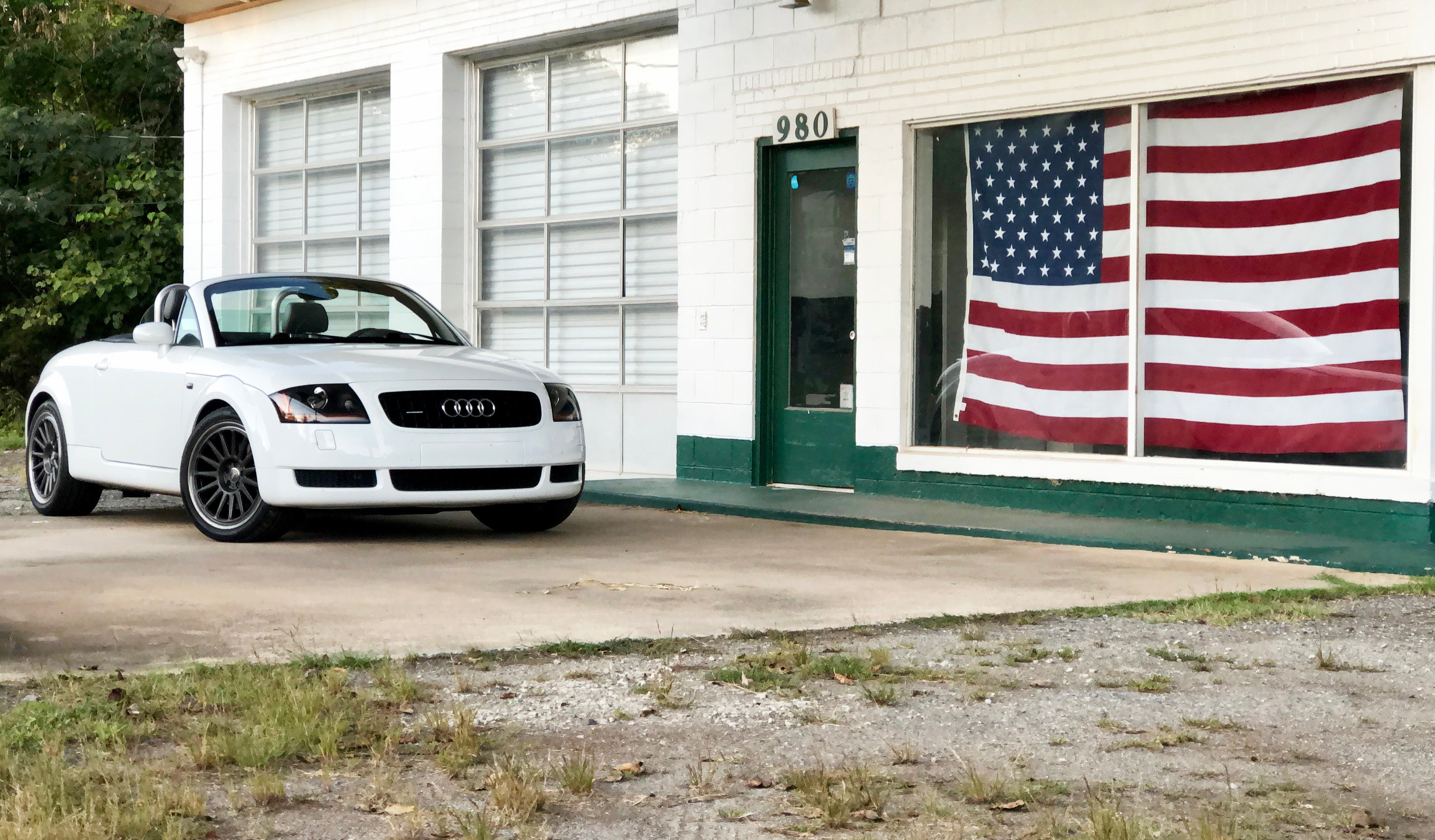 Audi convertible parked outside a building with an American flag in the window, showcasing a stylish automotive lifestyle.