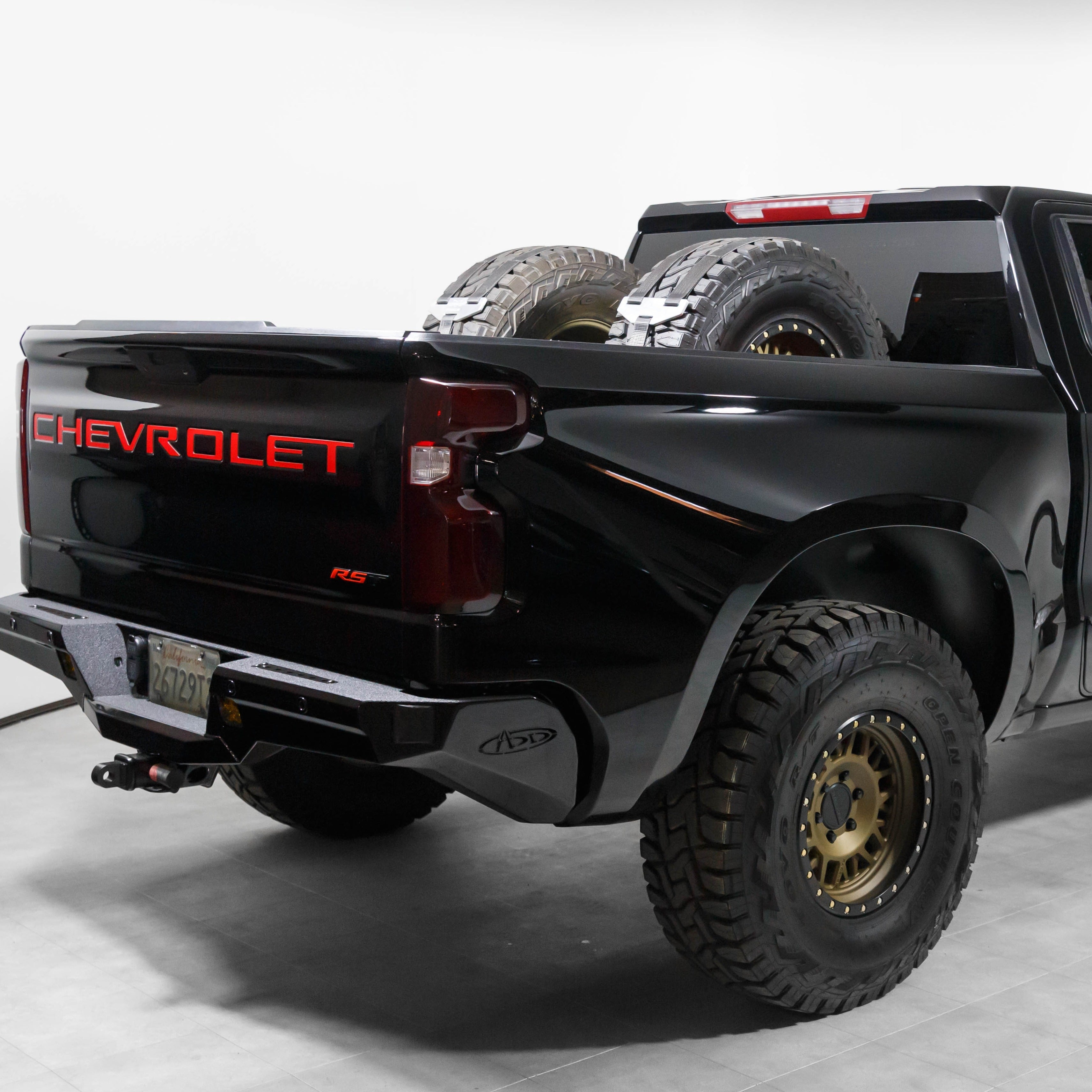 2019-2021 Chevrolet Silverado with custom bedsides, showcasing a sleek black finish and offroad tires in the truck bed.