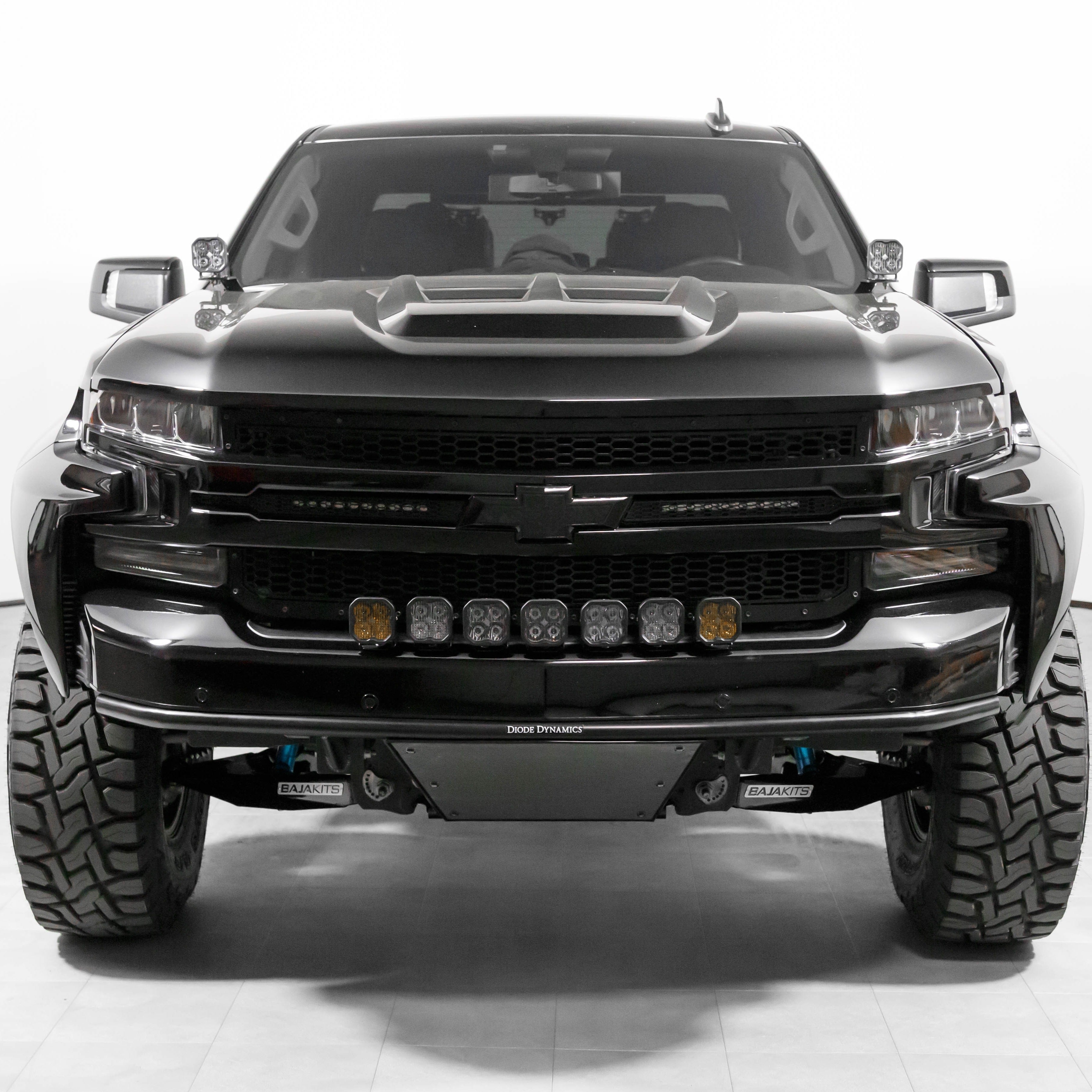 Front view of a modified 2019-2021 Chevrolet Silverado with an aggressive hood design and offroad lights.