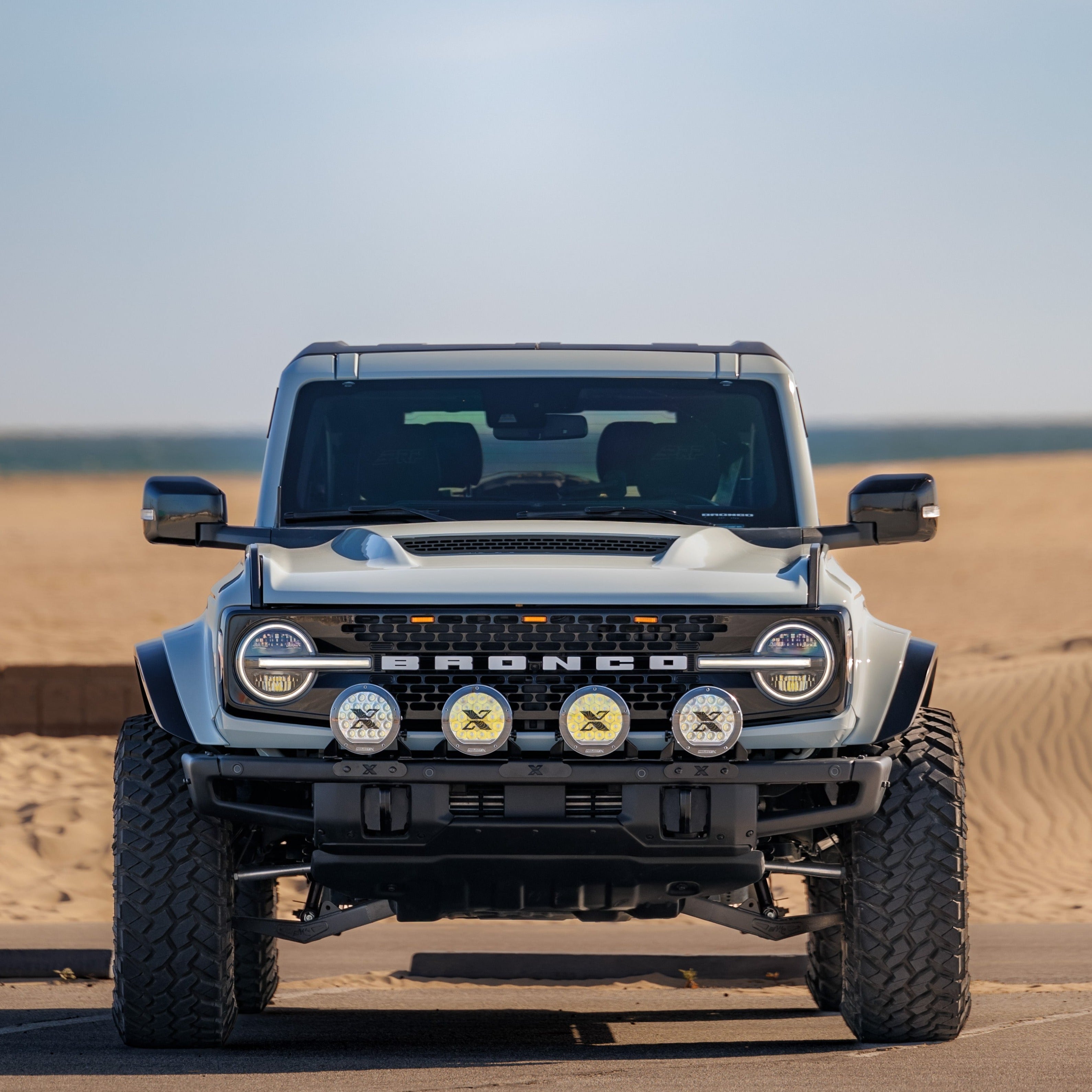 2021-2024 Ford Bronco with a Ram Air Hood, showcasing offroad lights and rugged design on a sandy terrain.
