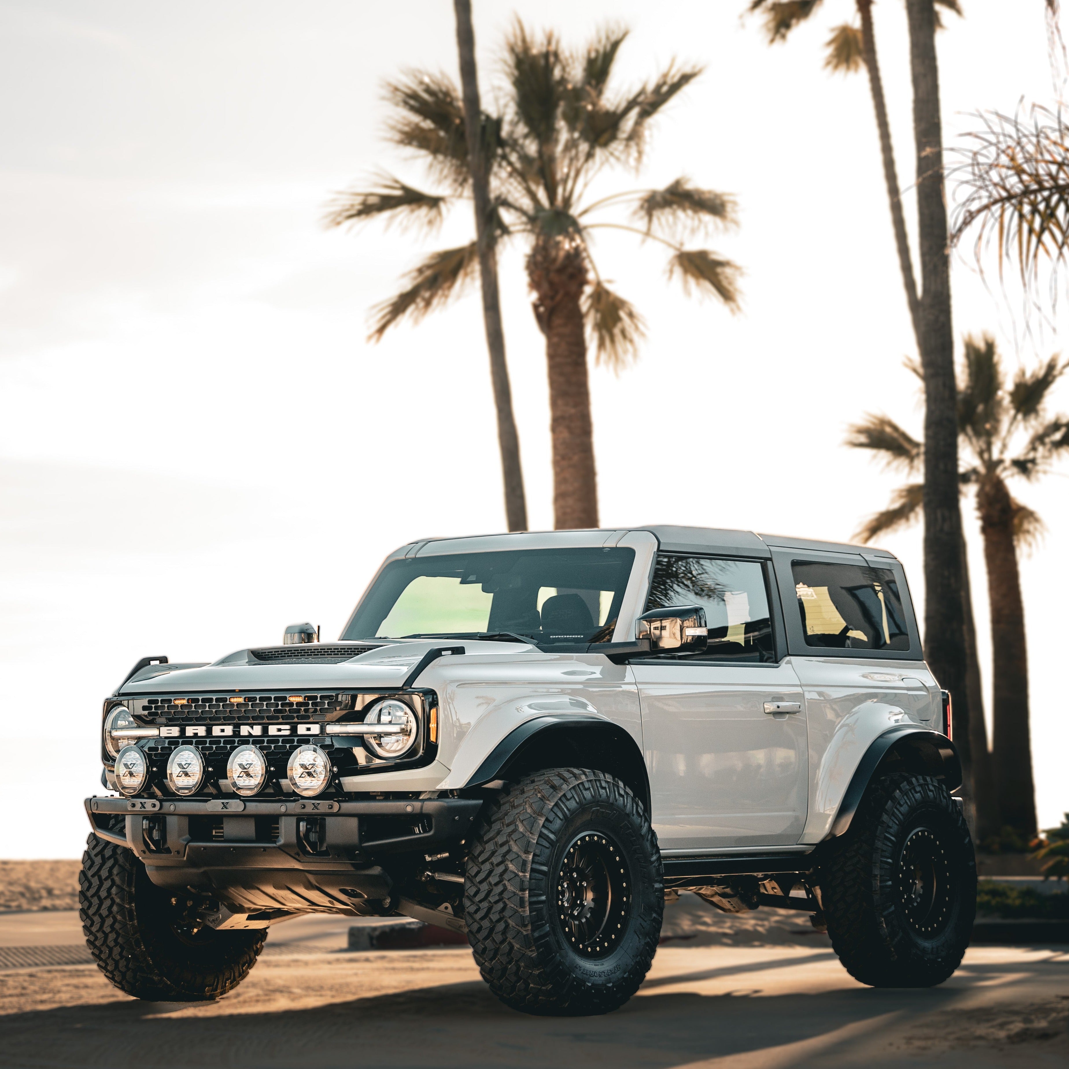 2021-2024 Ford Bronco with custom fenders, showcasing offroad capabilities against a palm tree backdrop.