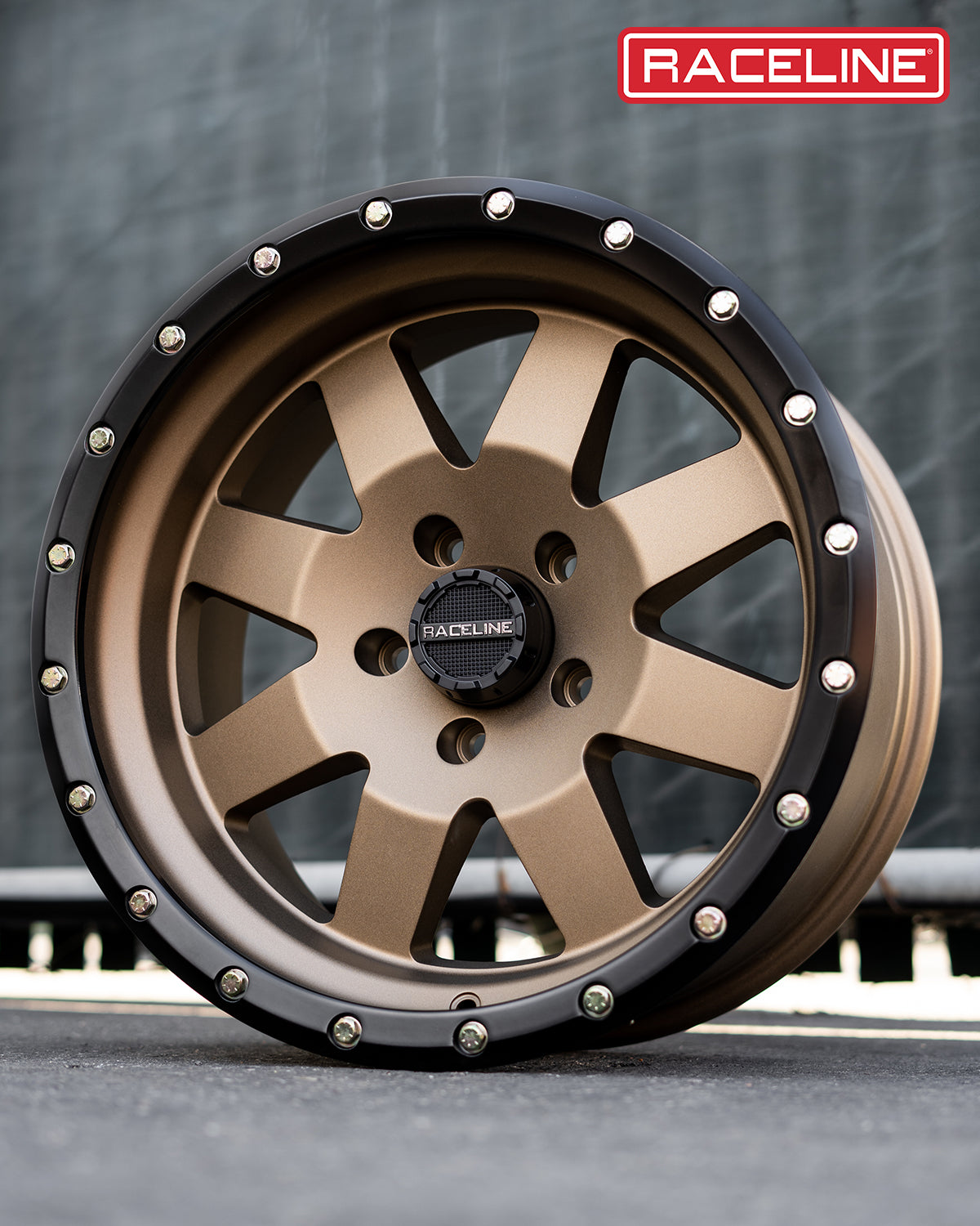 Raceline 935BZ Defender wheel showcasing a bronze finish with black accents and decorative bolts, ideal for offroad vehicles.