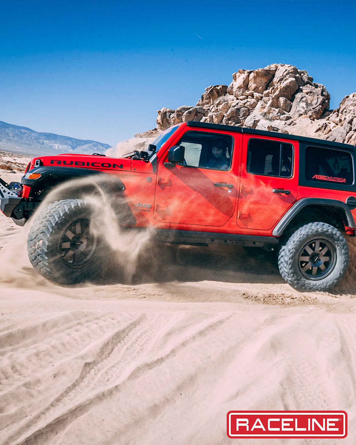 Red Jeep Rubicon 935G Defender driving through sandy terrain, showcasing off-road capabilities and rugged design.