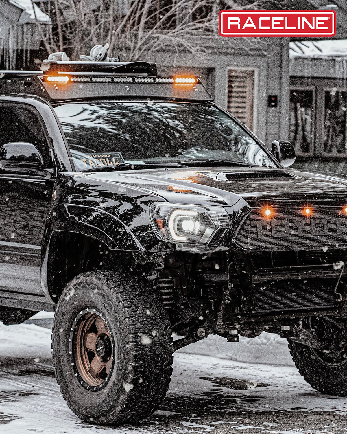 Black Toyota Tacoma equipped with Raceline 937BZ Combat wheels, showcasing off-road capabilities in a snowy environment.
