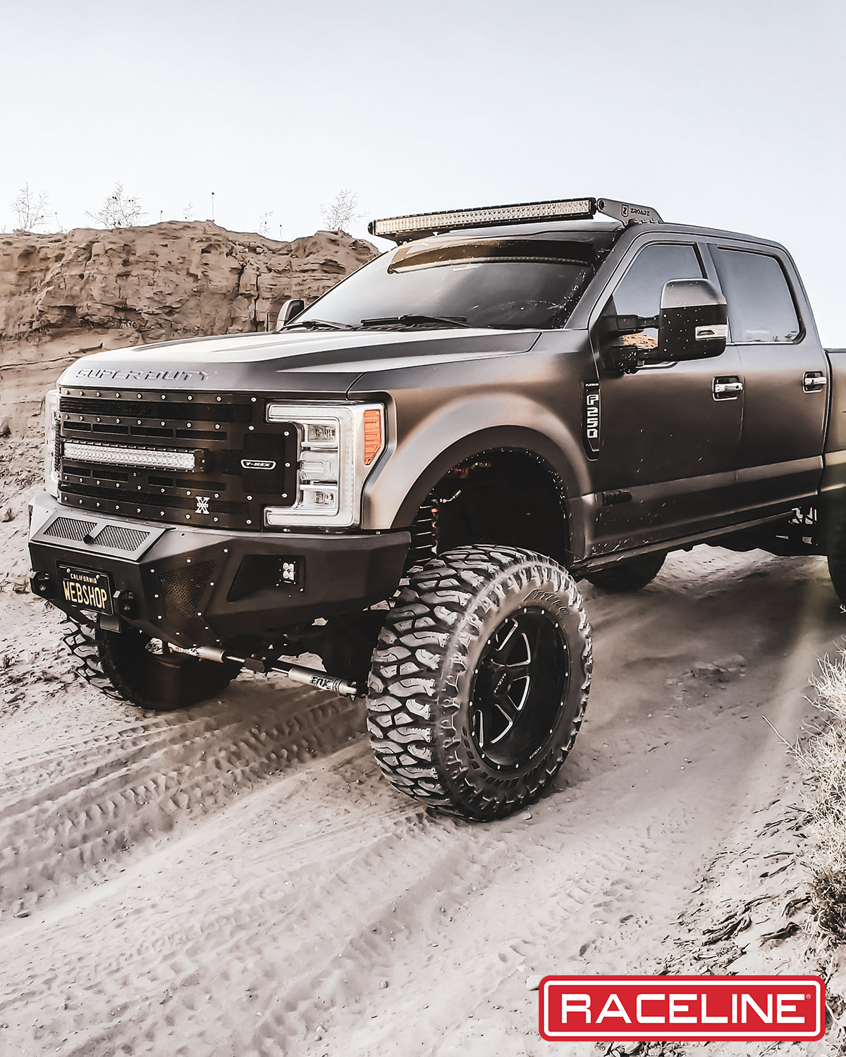 Matte black lifted truck with oversized tires and off-road accessories, showcasing rugged design and performance.
