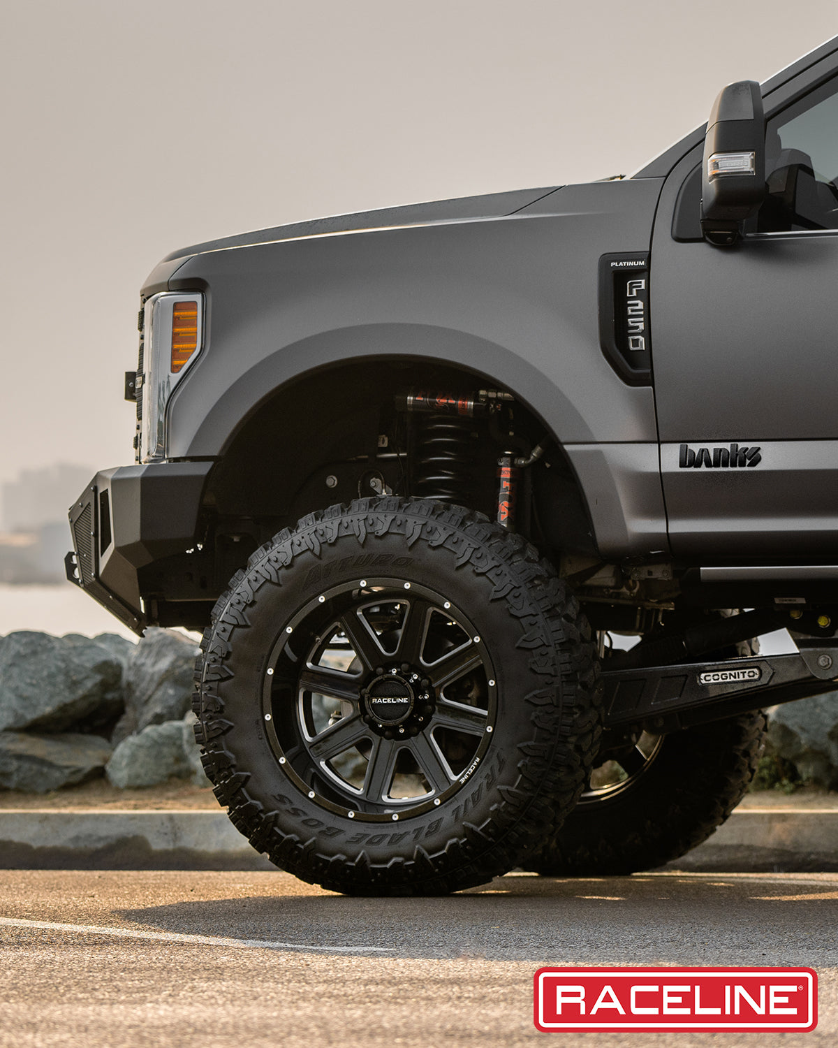 Close-up of a lifted truck featuring Raceline 940M Hostage wheels and rugged off-road tires, showcasing enhanced suspension.