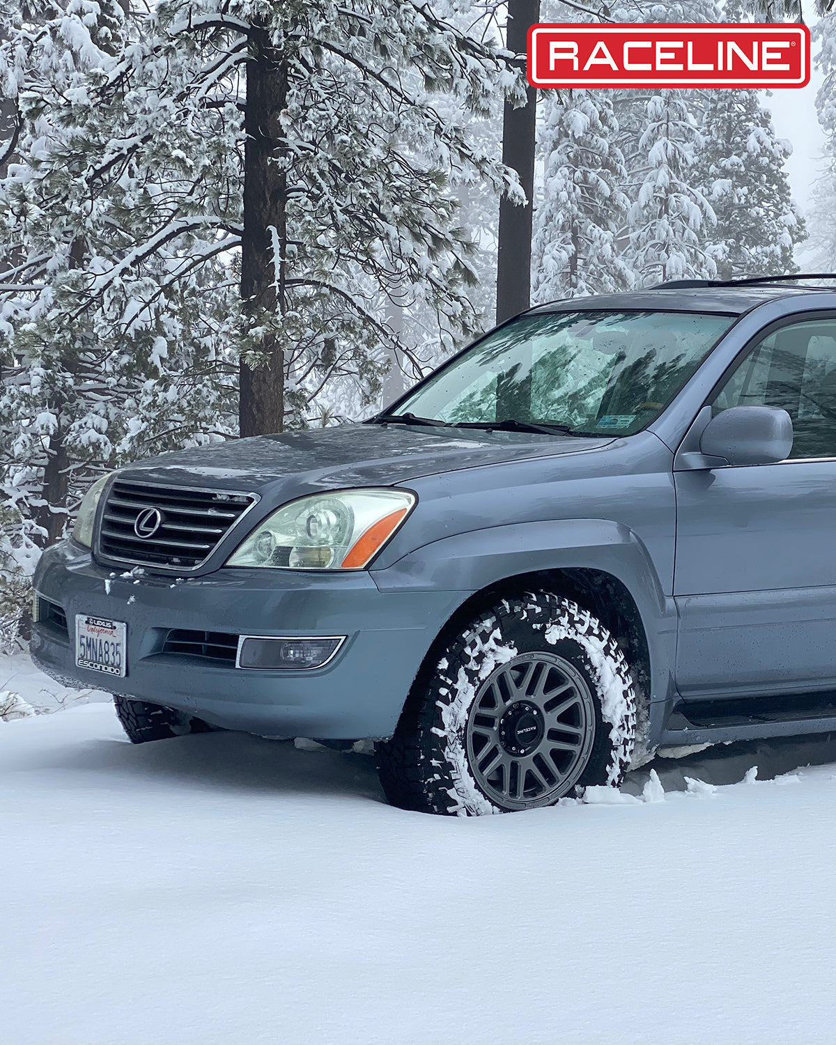 Lexus SUV equipped with Raceline wheels, parked in deep snow among tall trees, showcasing off-road capability.