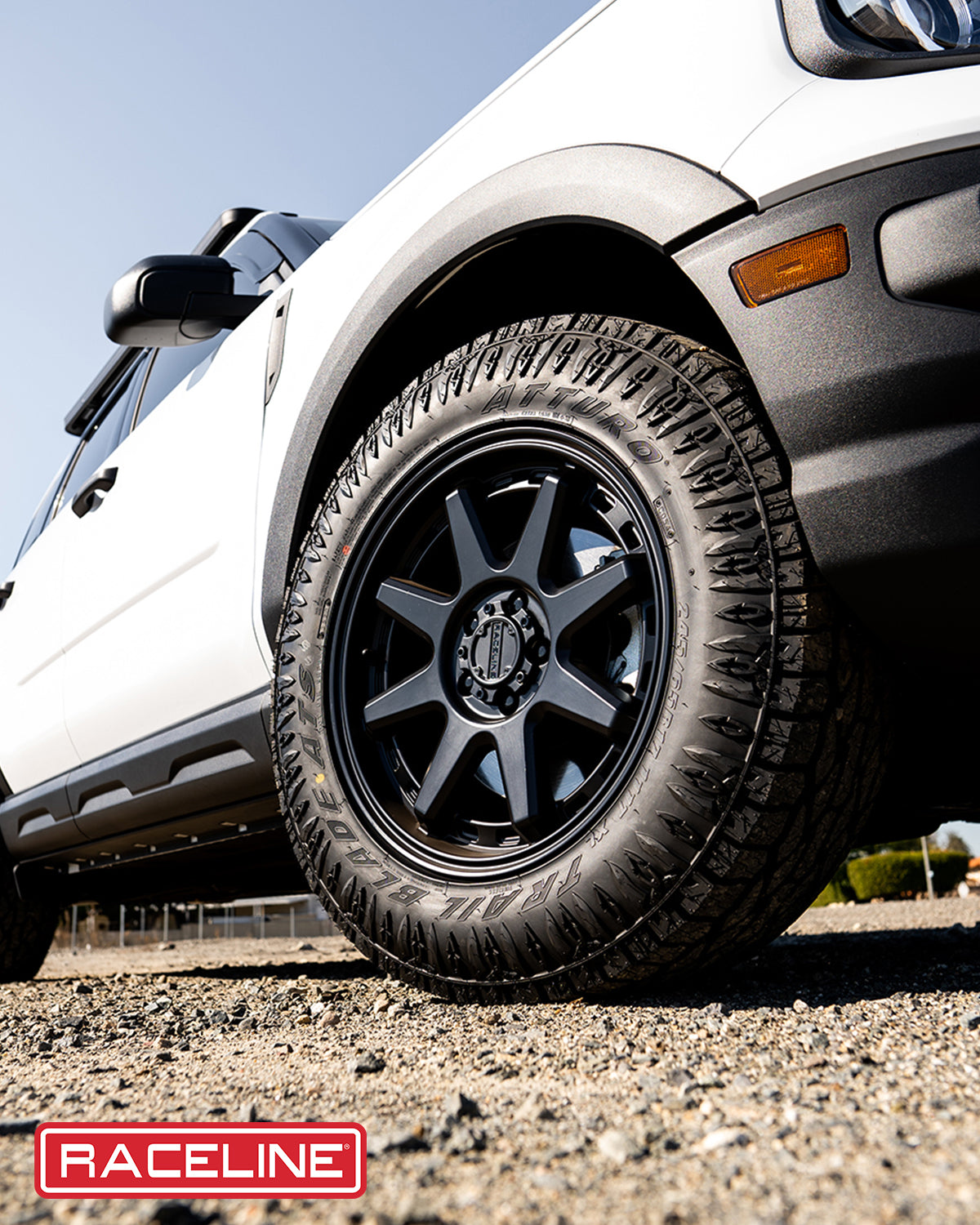 Black Raceline 947B Scout wheel on a white SUV, showcasing rugged tire tread and off-road capability.