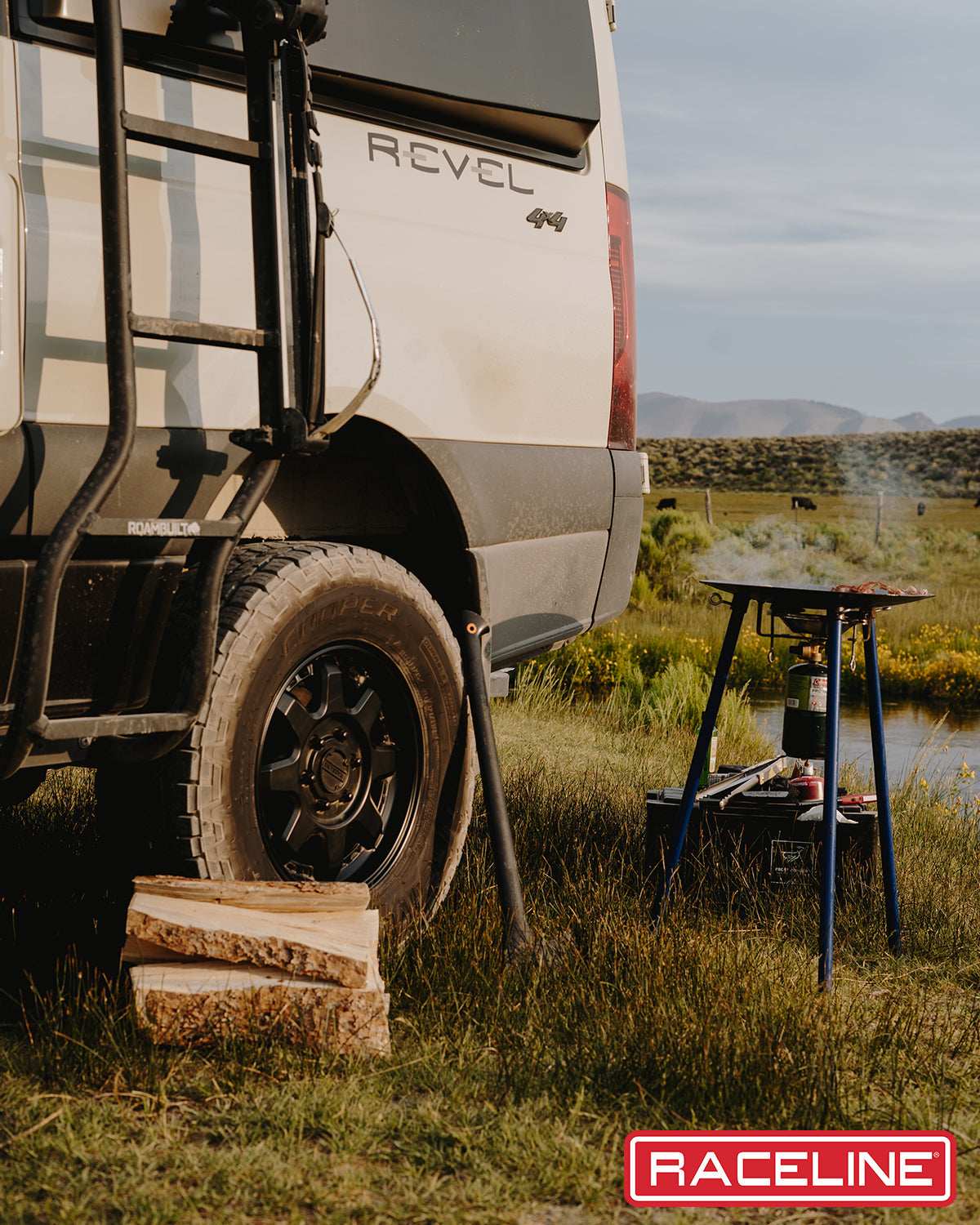 Scout Van parked in a scenic outdoor setting with a portable stove and firewood nearby, showcasing adventure-ready features.