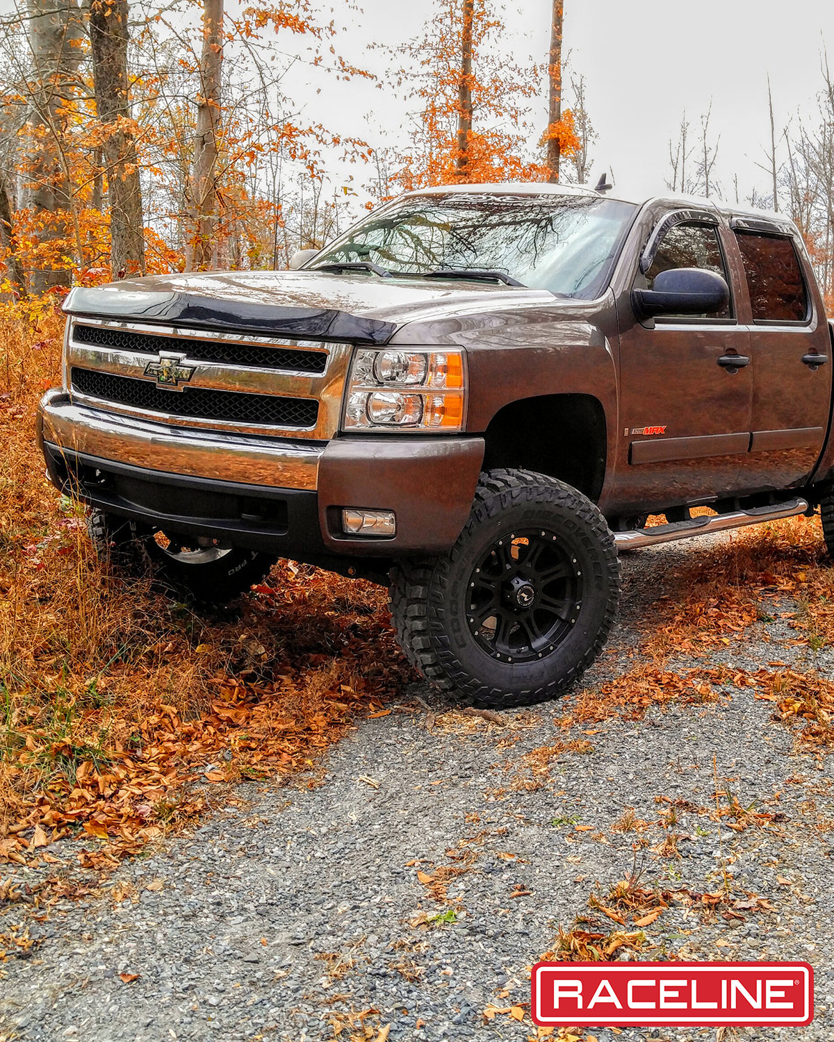 Black 981 Raptor wheels on a lifted truck parked in a forest with autumn foliage, showcasing rugged offroad capability.