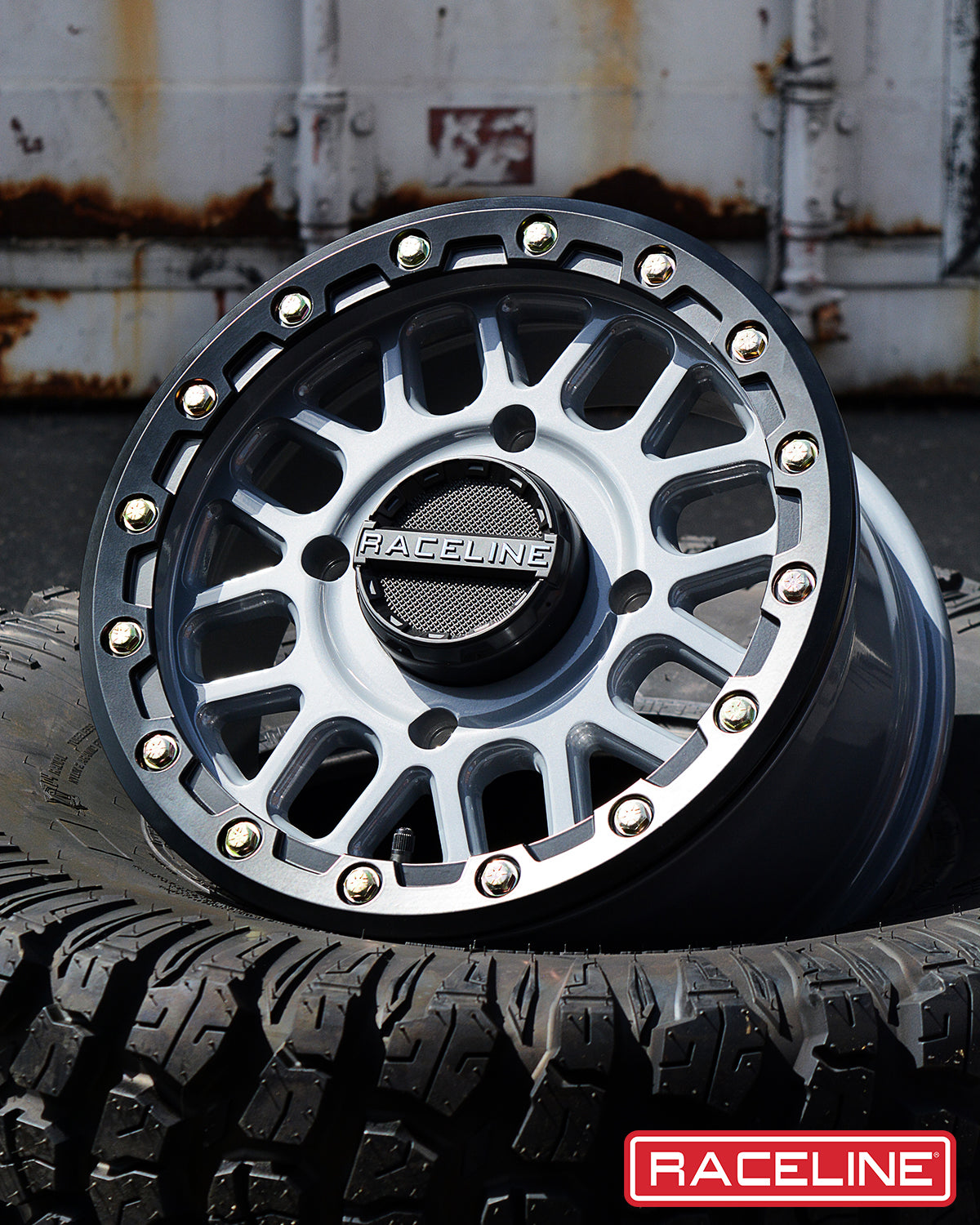A93SG Podium Beadlock wheel displayed on a tire, featuring a sleek design with silver accents and a durable finish.