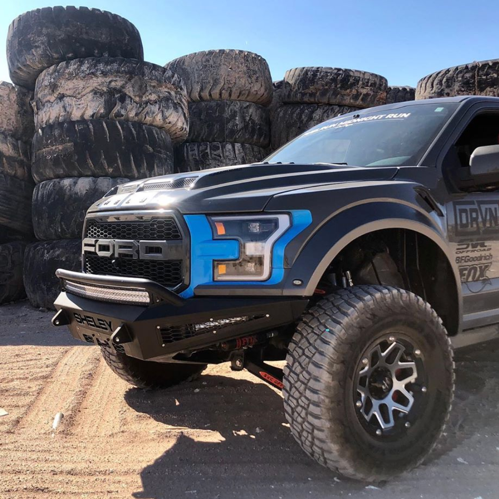 2017-2020 Ford Raptor fenders showcased on a modified truck in an offroad setting with large tires in the background.