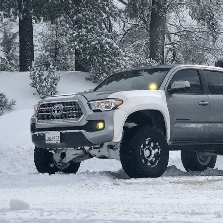 2016-2022 Toyota Tacoma fenders showcased on a lifted truck in a snowy landscape, highlighting offroad capabilities.