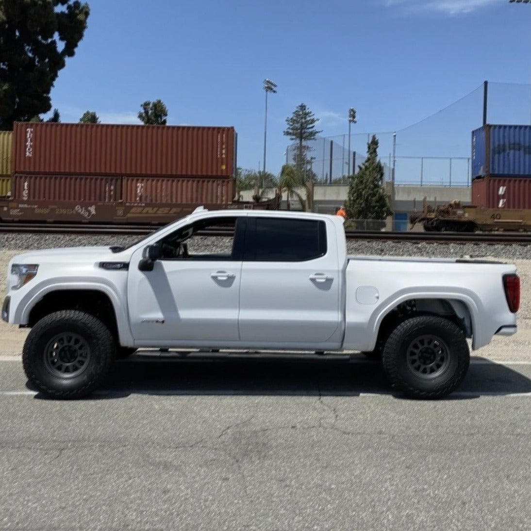 2019-2021 GMC Sierra with aftermarket bedsides, showcasing a lifted stance and off-road tires on a sunny day.