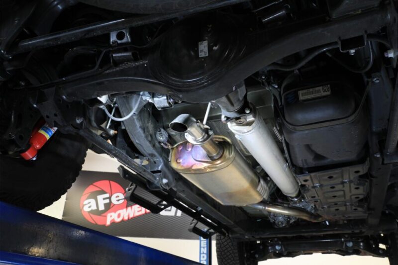 aFe Rock Basher axle-back exhaust system installed under a Toyota Tacoma, showcasing the exhaust pipe and muffler design.