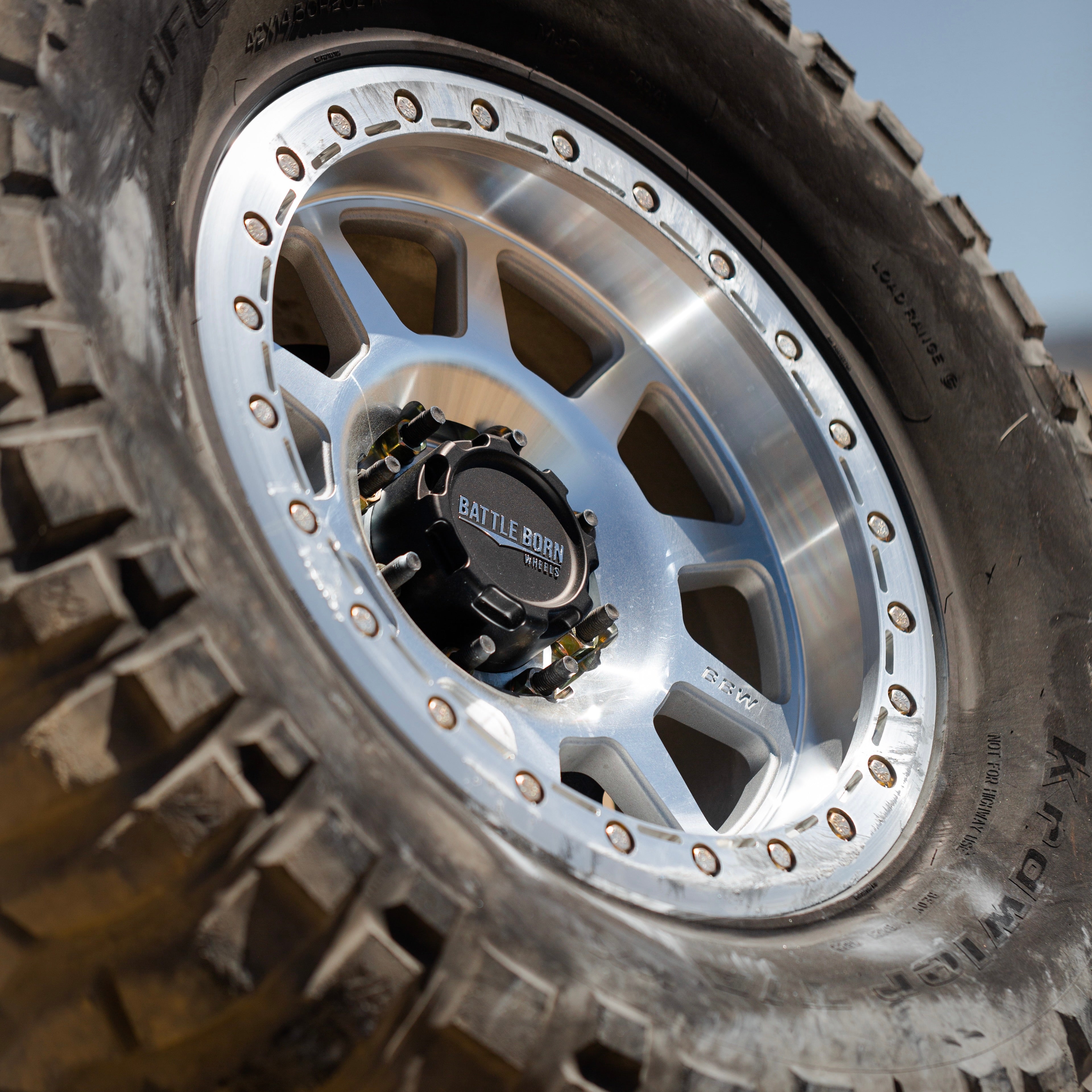 8 lug plastic center cap mounted on a polished wheel, showcasing rugged tire tread for offroad vehicles.