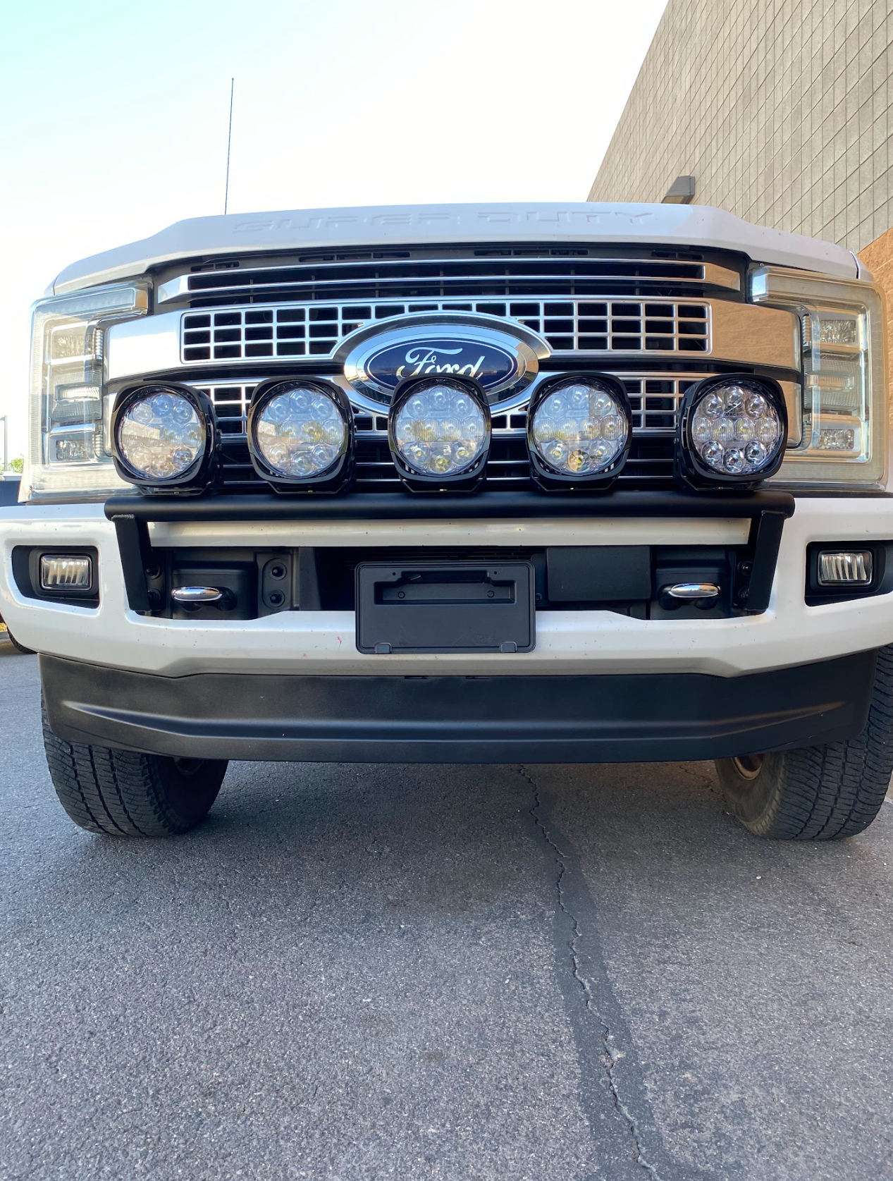 Front view of a 2017-2022 Ford F-250 Super Duty with a light mount kit installed on the stock bumper, featuring four auxiliary lights.