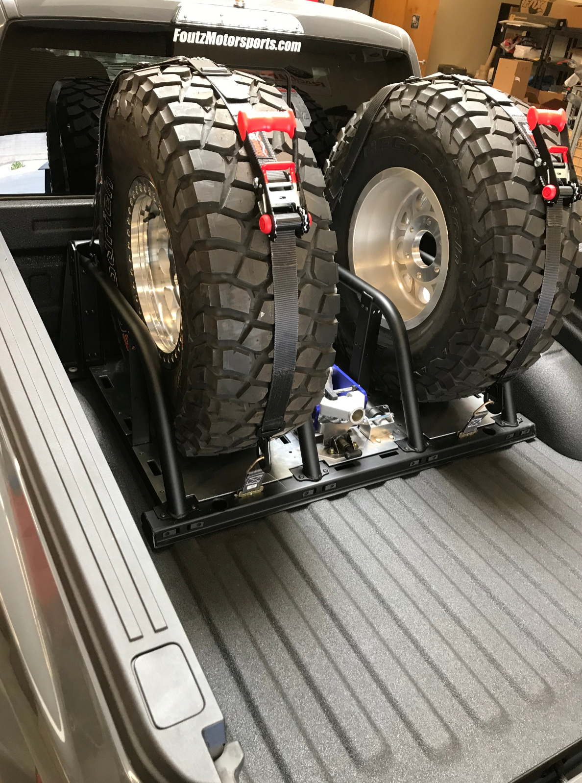 2021+ Raptor 5-Link Rear Bed Organizer holding two spare tires securely in a truck bed with a sturdy frame.