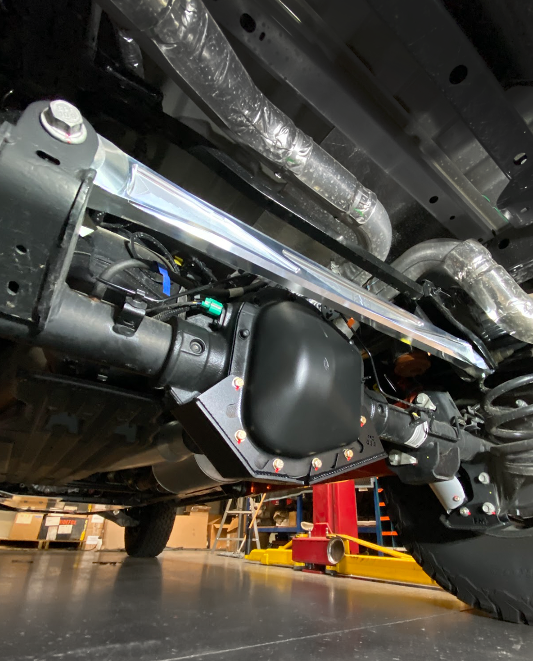 2021-2024 F150 Raptor billet panhard bar with ultra-flex joint installed under a truck for enhanced stability and performance.