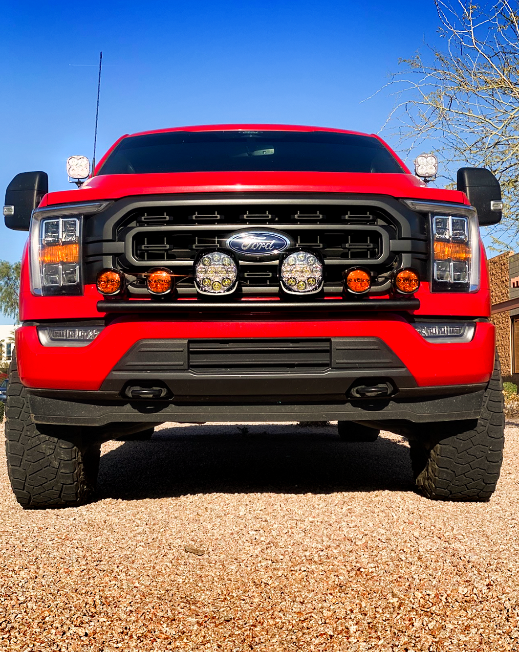 Front view of a red 2021-2023 Ford F150 featuring a front light mount for stock bumper with multiple auxiliary lights.