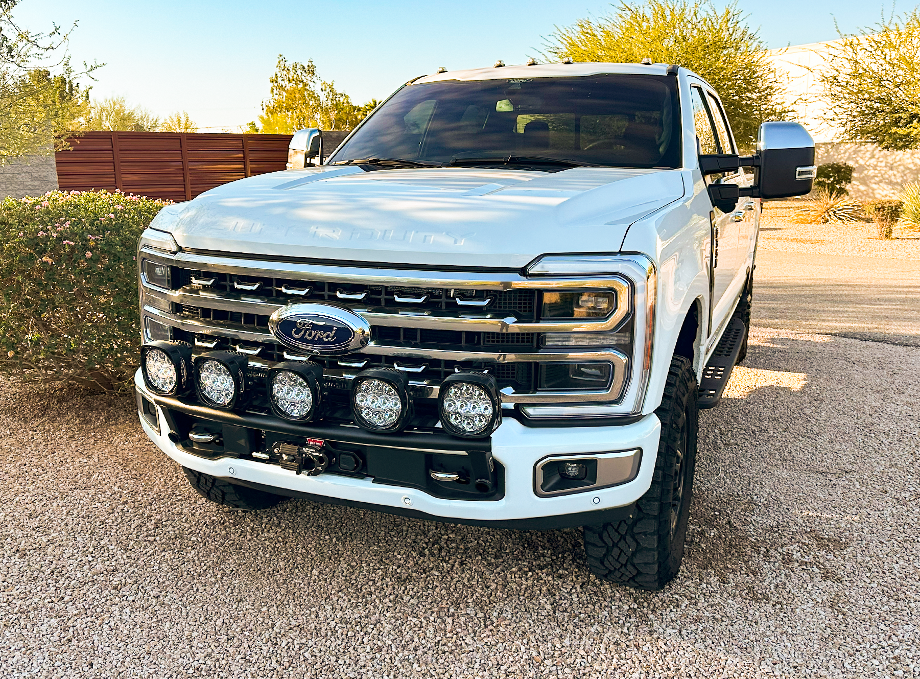 2023+ Ford F-250 Super Duty with front light mount kit installed on stock bumper, showcasing offroad lighting setup.