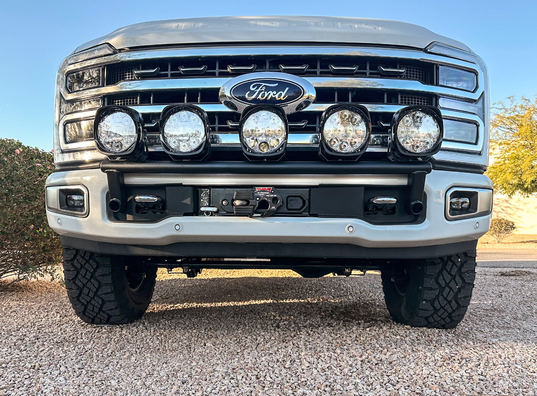 2023+ Ford F-250 Super Duty front light mount kit installed on stock bumper, featuring multiple off-road lights.