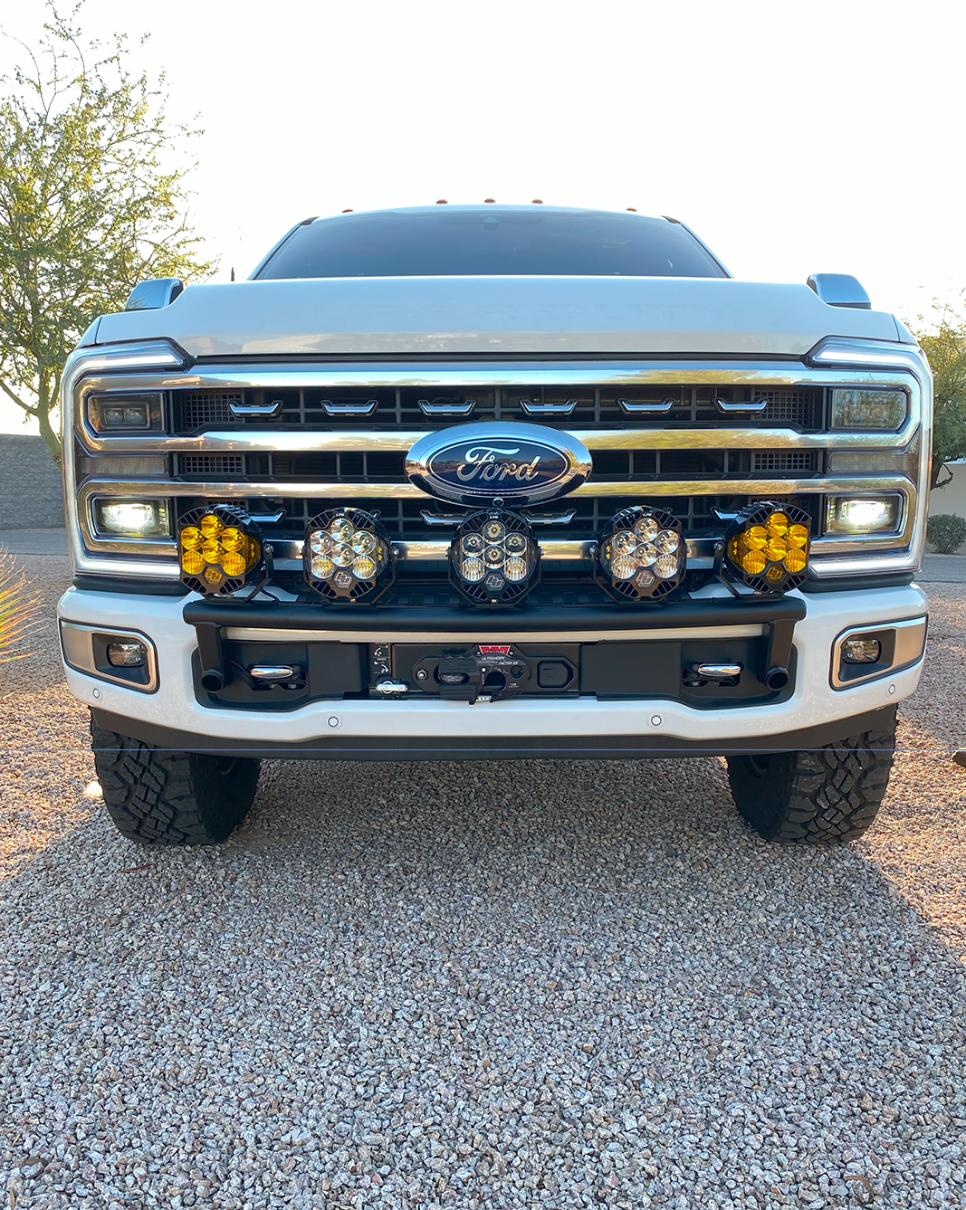 Front view of a 2023 Ford F-250 Super Duty with a light mount kit installed on the stock bumper, showcasing offroad lights.