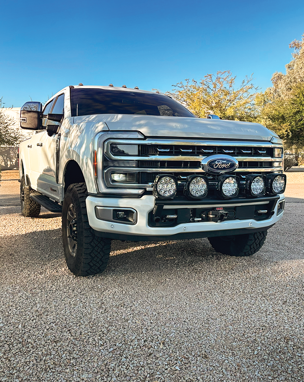 2023+ Ford F-250 Super Duty with front light mount kit installed on stock bumper, showcasing offroad lighting setup.