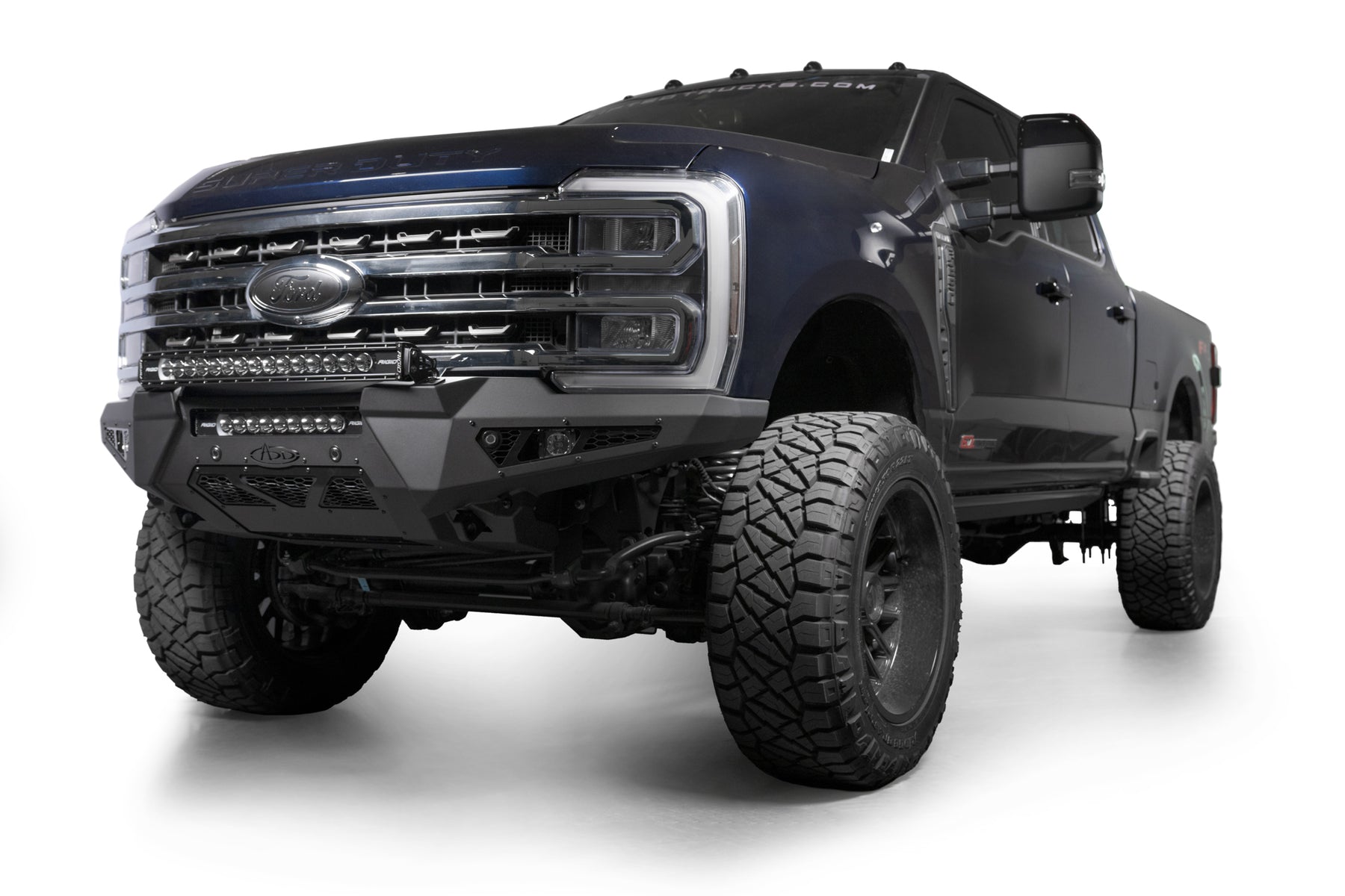 Addictive Desert Designs 2023+ Ford Super Duty Honeybadger Front Bumper on a lifted truck with aggressive tires.