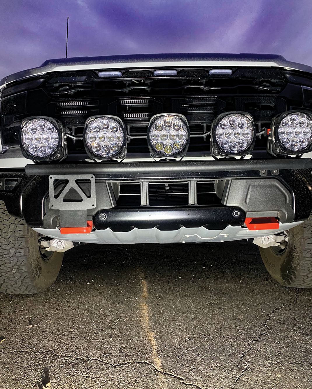Front view of a 2024 Gen 3.5 Raptor featuring a tow hook license plate mount and multiple LED lights.