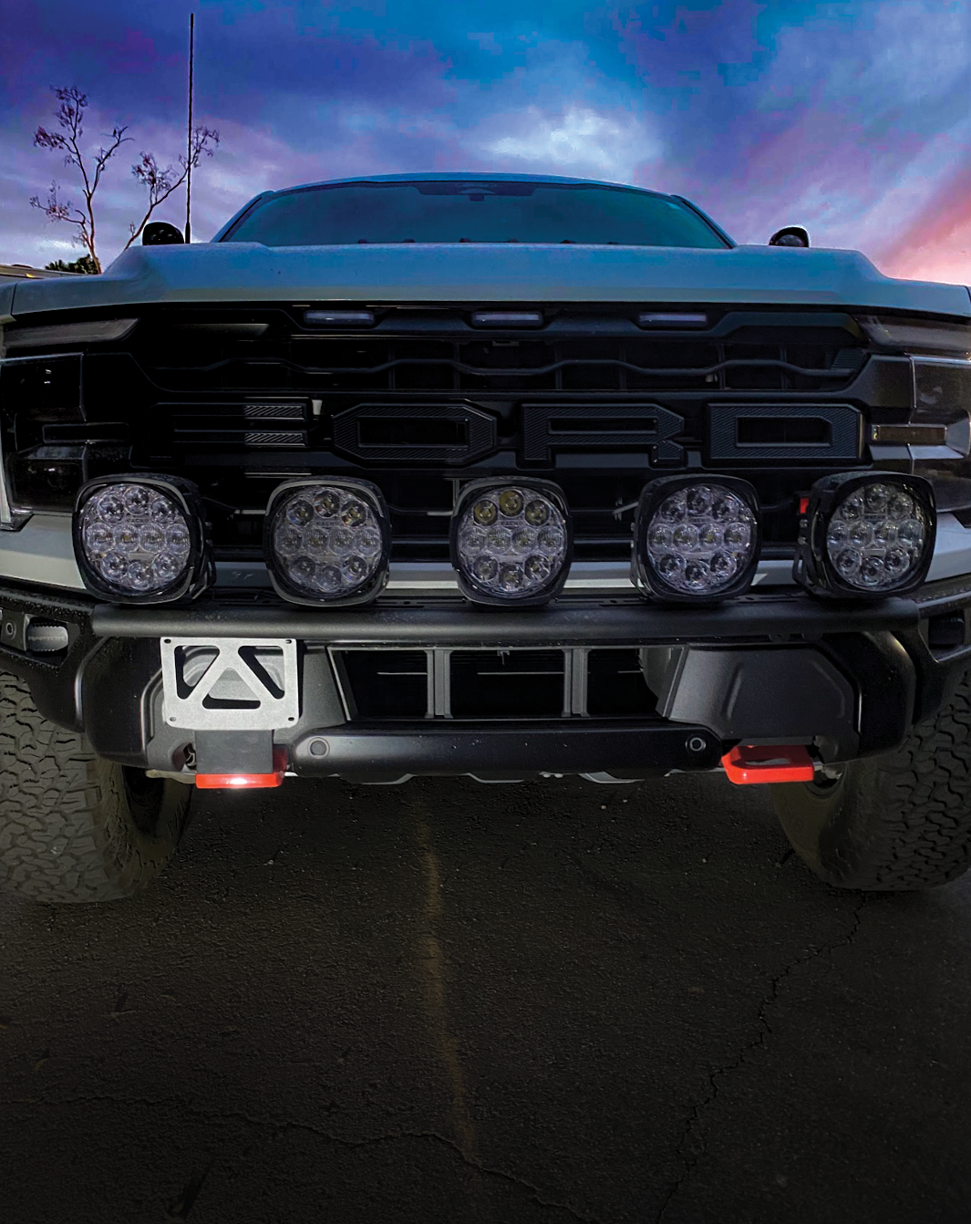 Front view of a 2024+ Gen 3.5 Raptor showcasing a front tow hook license plate mount and LED light bar.