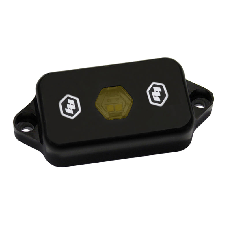 Baja Designs LED Rock Light in amber color, featuring a compact black housing with two logo emblems.