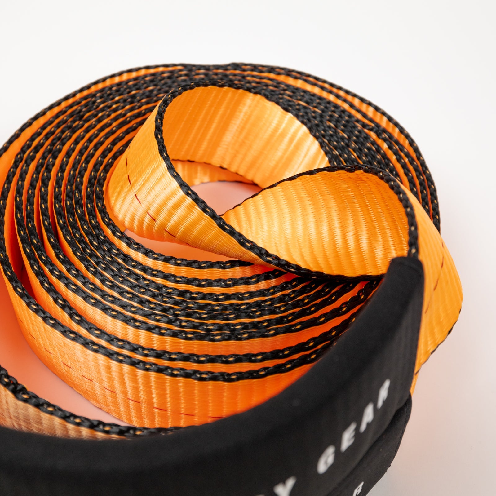 30-foot flat strap in orange and black, coiled neatly for easy storage, ideal for towing and recovery applications.