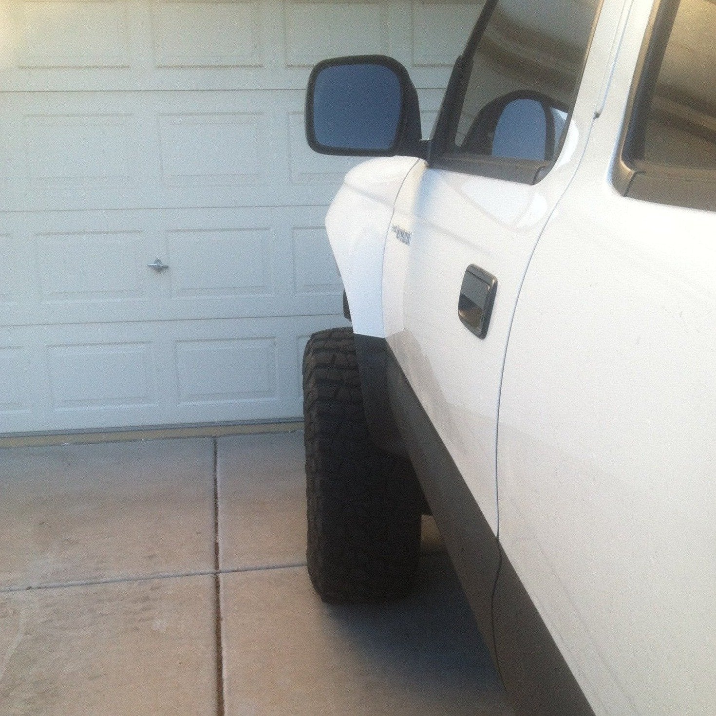 1995-2004 Toyota Tacoma fenders showcased on a lifted white truck parked in a driveway.