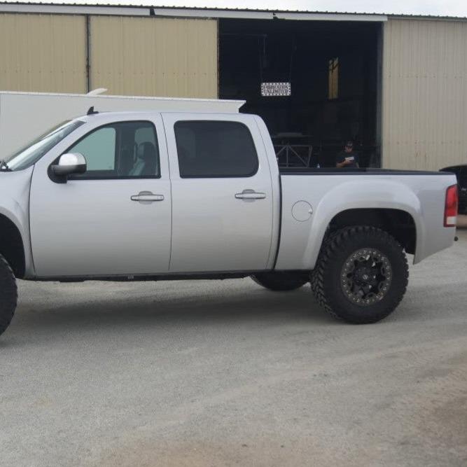 2007-2013 GMC Sierra with custom bedsides, showcasing an elevated stance and rugged off-road tires.