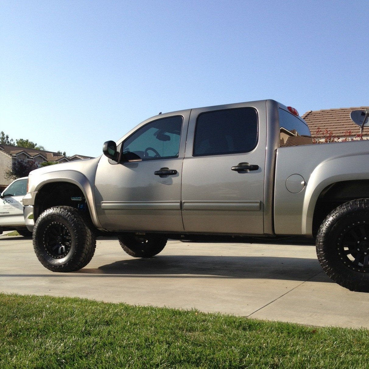 2007-2013 GMC Sierra with aftermarket fenders, showcasing a lifted stance and offroad tires in a residential setting.