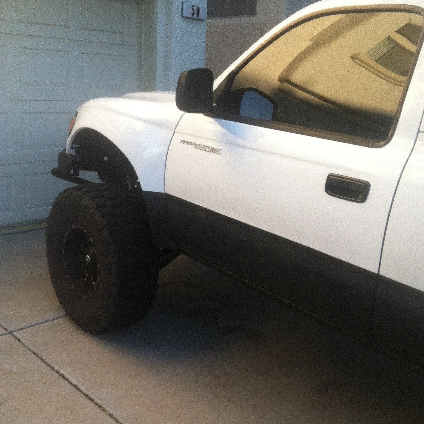 1995-2004 Toyota Tacoma fenders installed on a lifted white truck, showcasing offroad-ready design and rugged appearance.