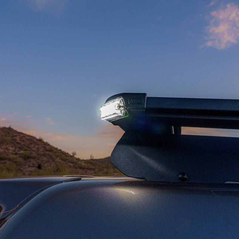 ARB Nacho Nano Base Rack Corner Cap 4-Light Kit mounted on a vehicle, illuminating the surroundings at dusk.