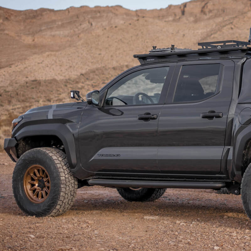 ARB Base Rack Cab Rack Mount and Deflector installed on a rugged truck in a desert landscape, showcasing offroad capability.