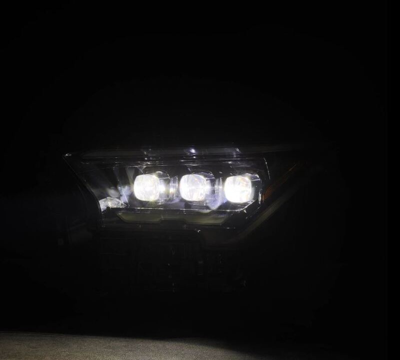 AlphaRex 2024 Toyota Tacoma NOVA-Series projector headlights in black with activation light, showcasing bright illumination.
