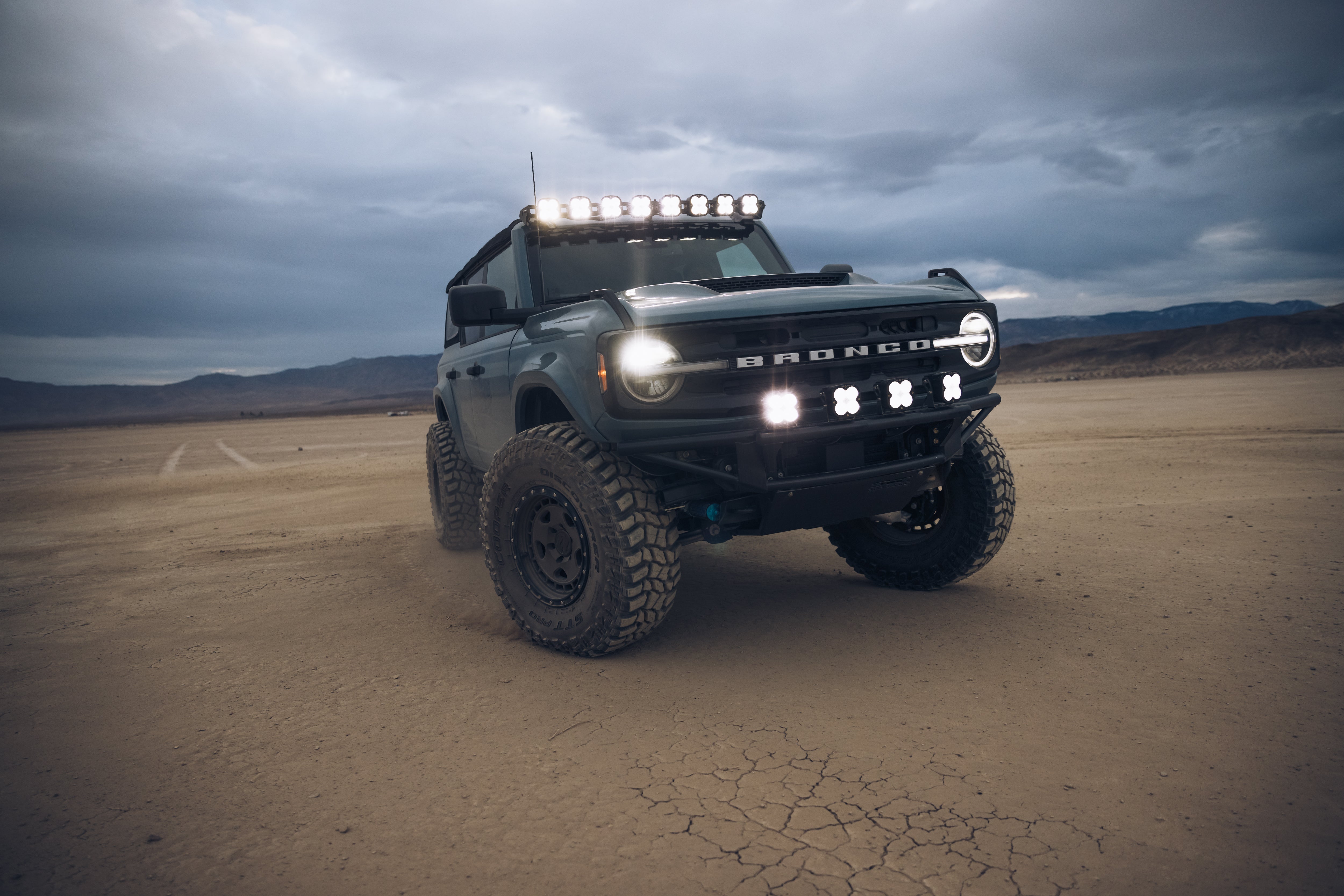 ADV Fiberglass 2021 Ford Bronco with off-road tires and LED light bar, set against a rugged desert landscape.