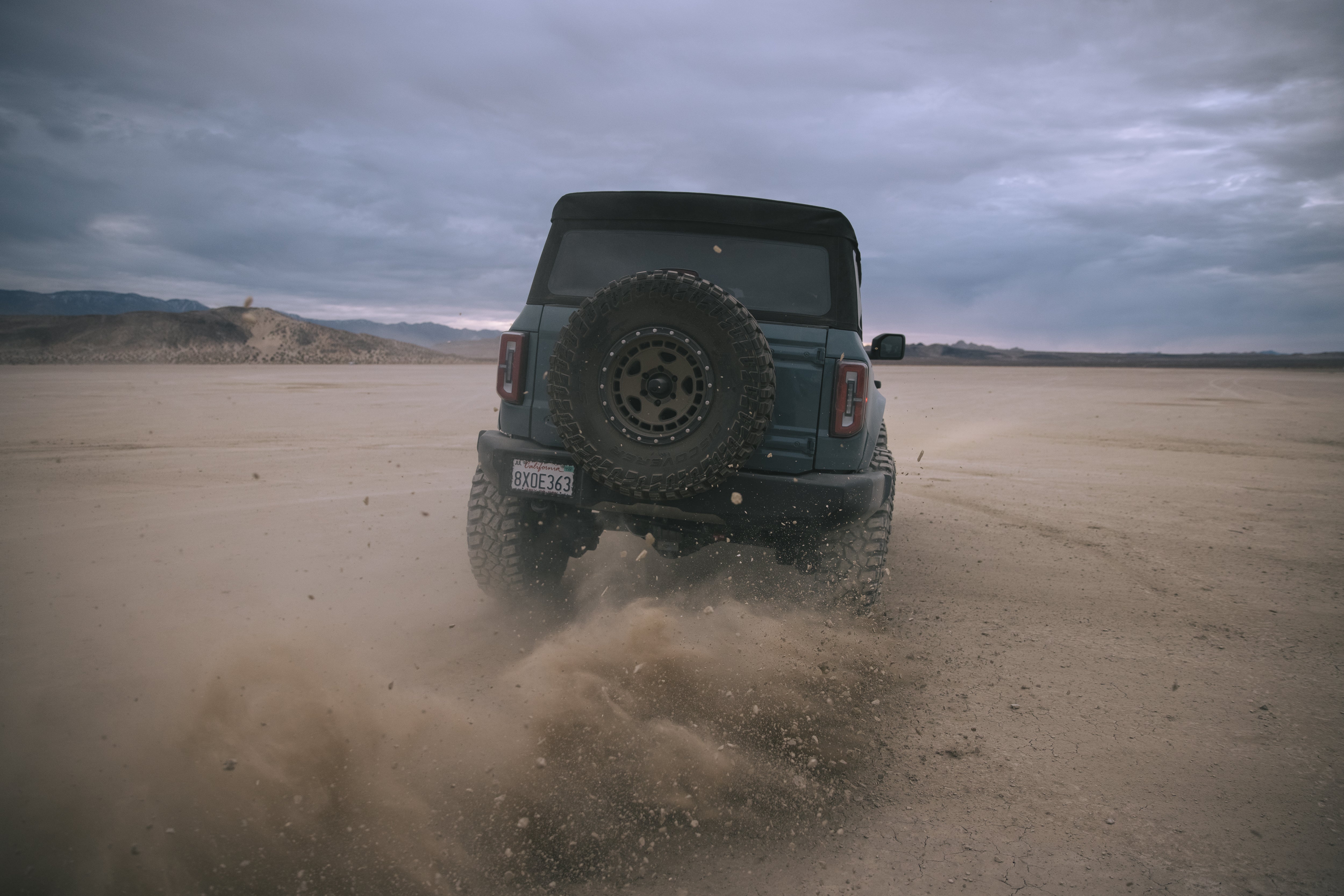 ADV Fiberglass 2021 Ford off-road vehicle kicking up dust in a rugged desert landscape, showcasing its performance capabilities.