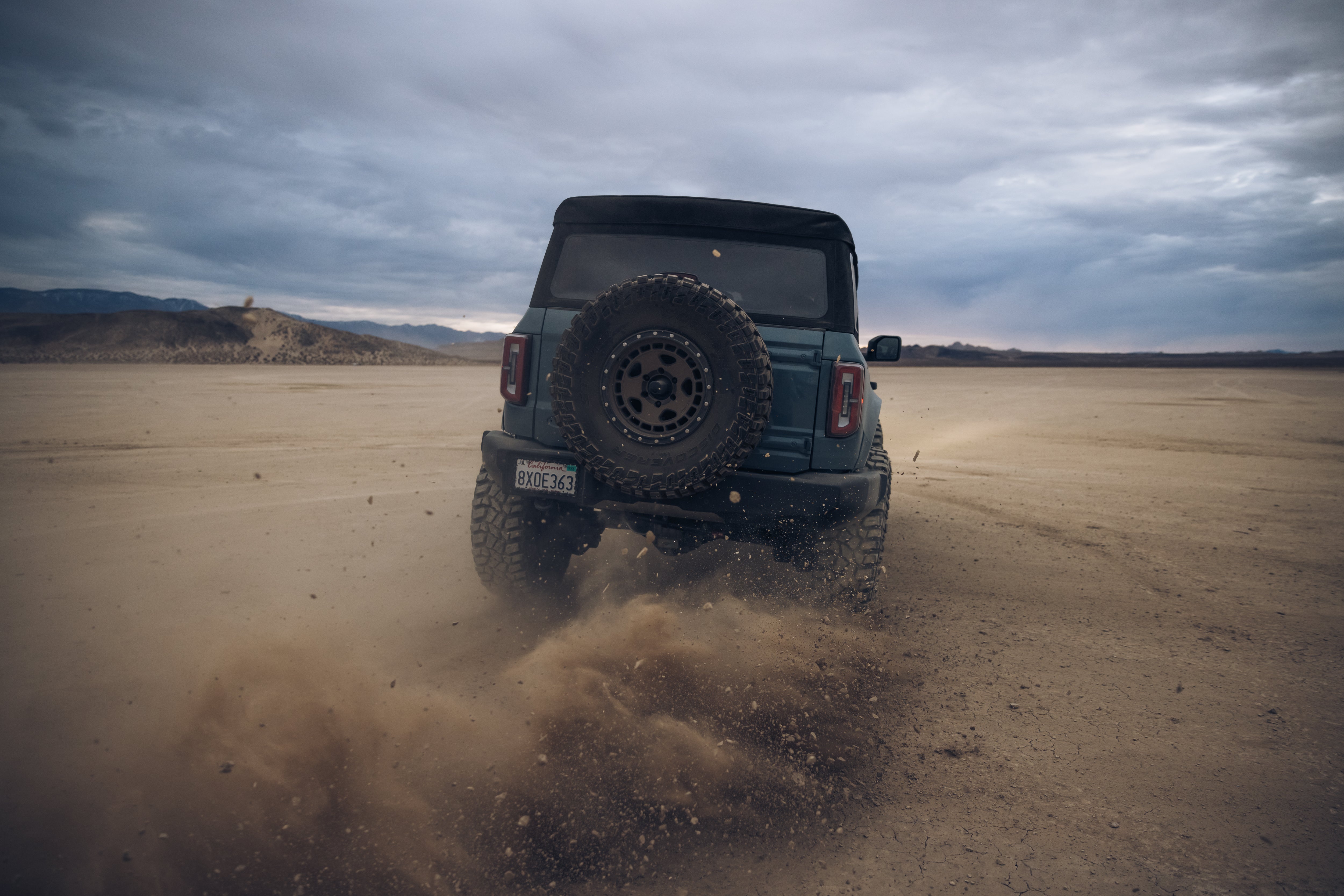 ADV Fiberglass 2021 Ford off-road vehicle kicking up dust in a desert landscape, showcasing rugged performance and style.