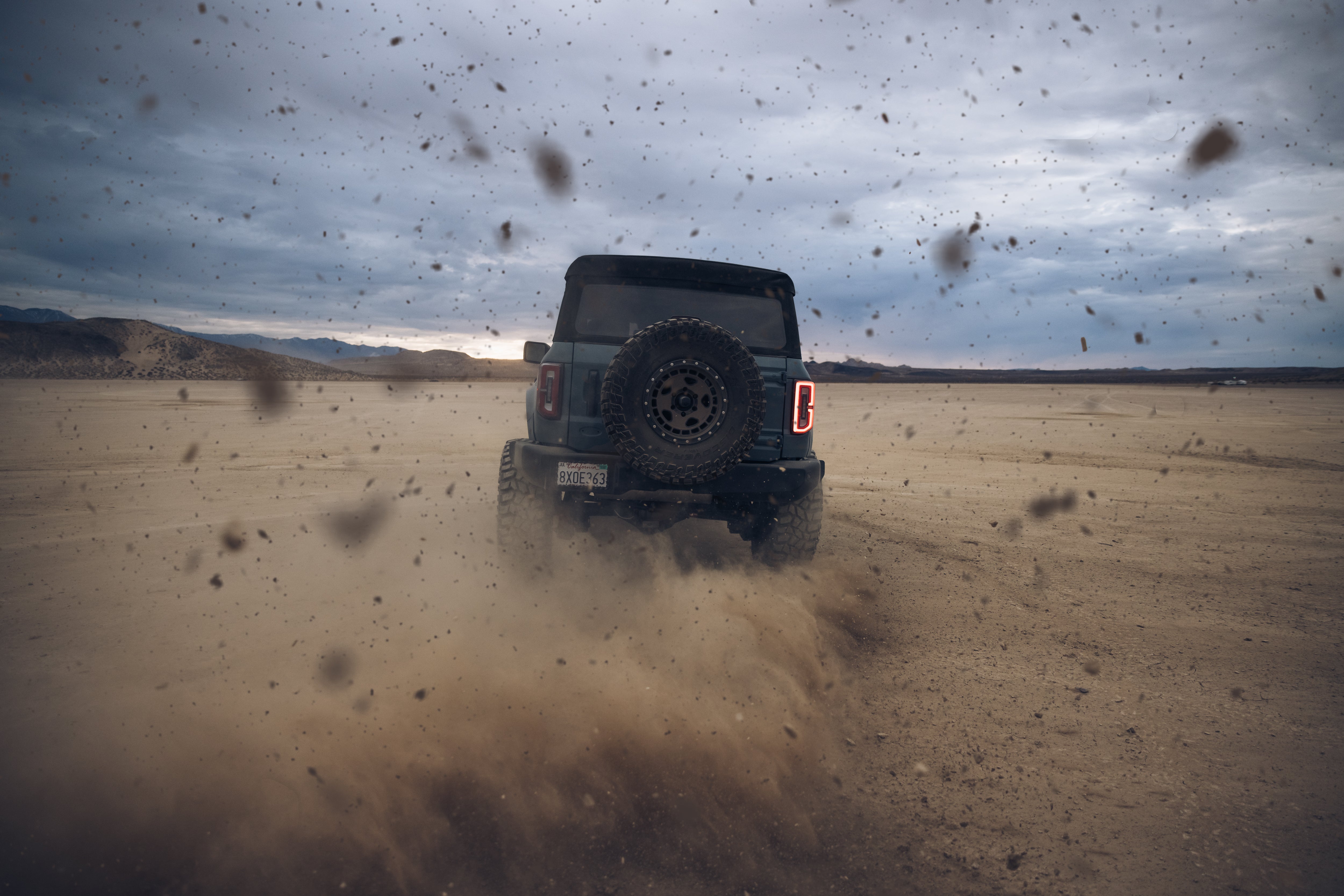 ADV Fiberglass 2021 Ford off-road vehicle kicking up dust in a desert landscape, showcasing rugged performance and durability.