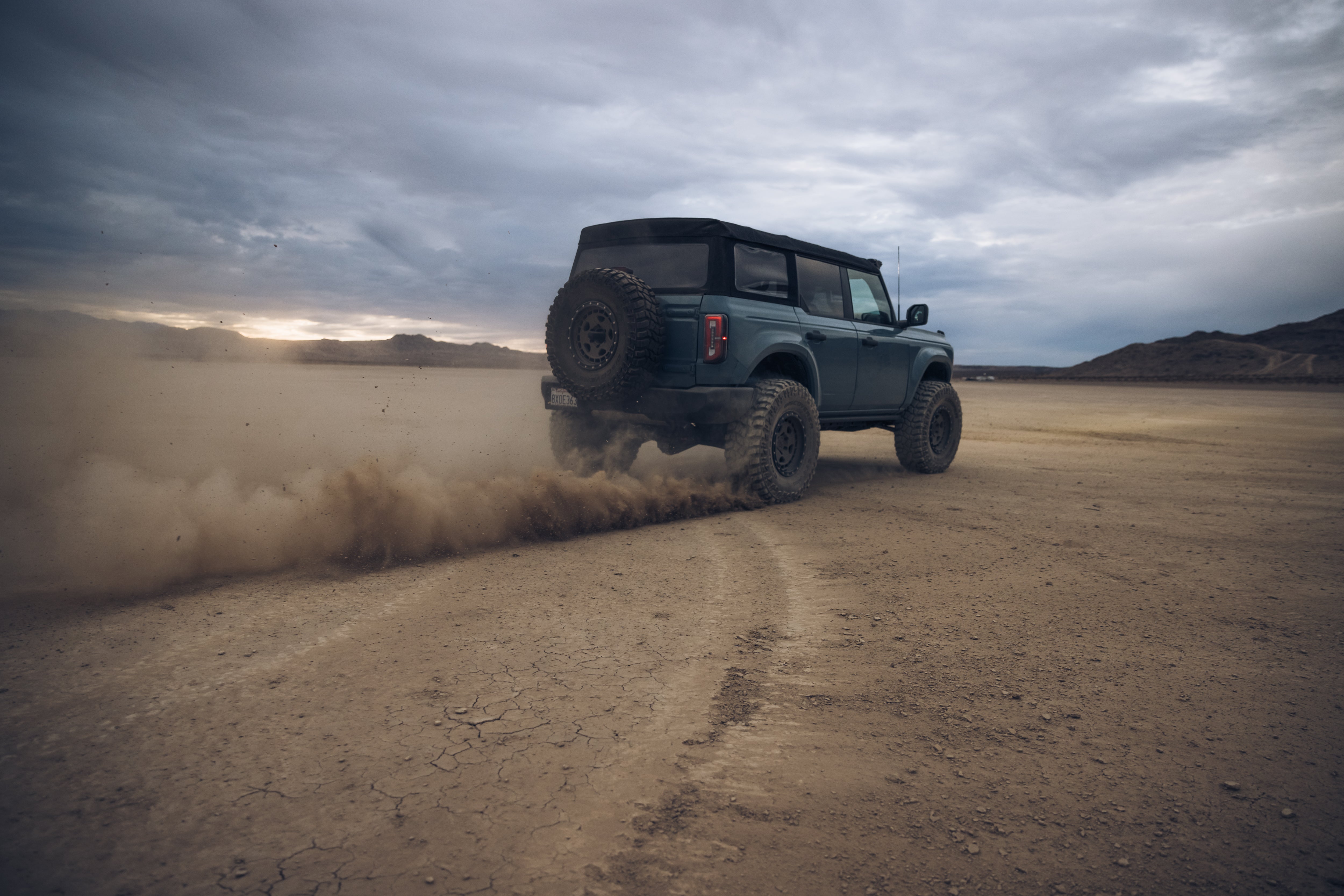 ADV Fiberglass 2021 Ford off-road vehicle kicking up dust on a rugged terrain, showcasing its durability and performance.